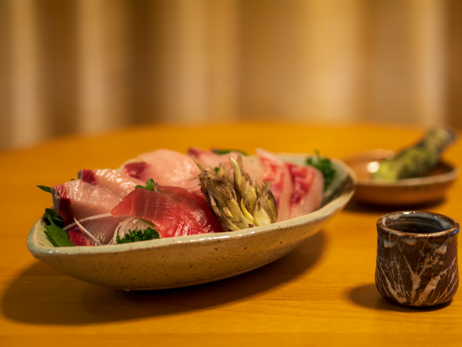 A beautiful plate of sashimi arranged with a small dish on the table