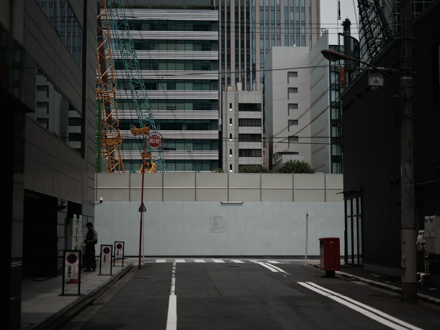 Scena urbana con alti edifici e un muro bianco lungo la strada