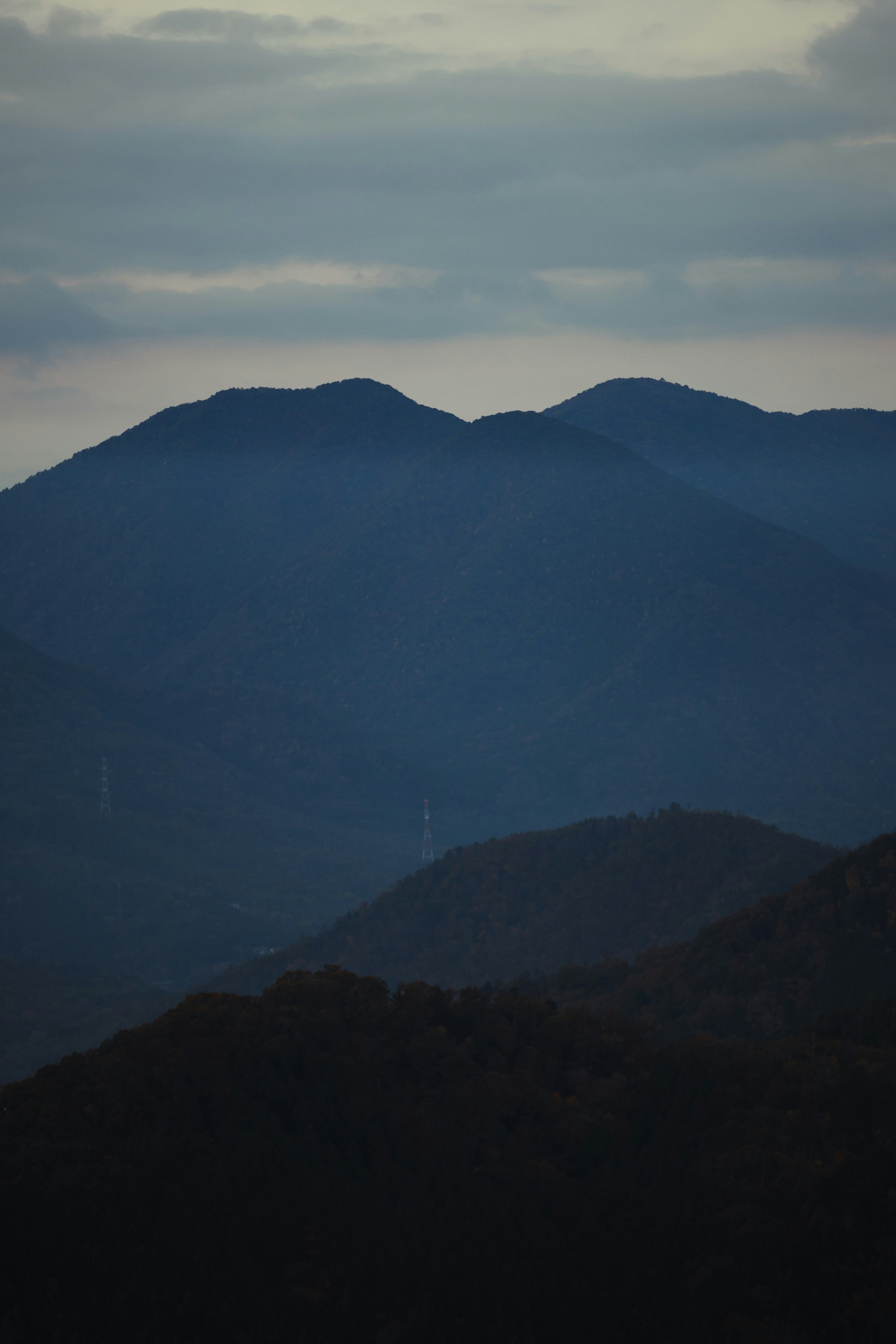 山並みのシルエットが重なる夕暮れの風景