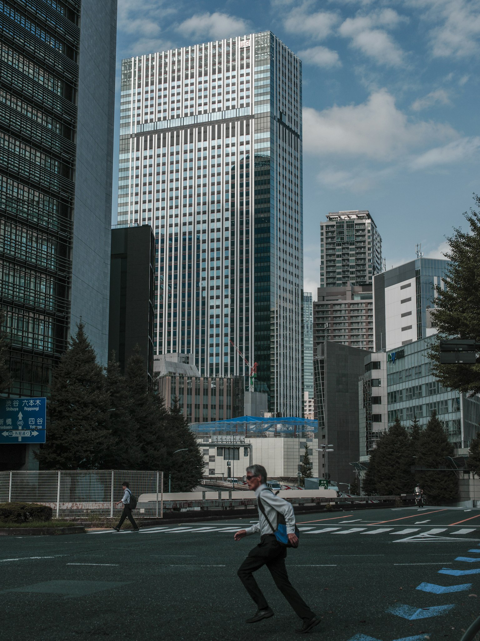 在晴朗天空下，人们在摩天大楼之间行走的城市风景