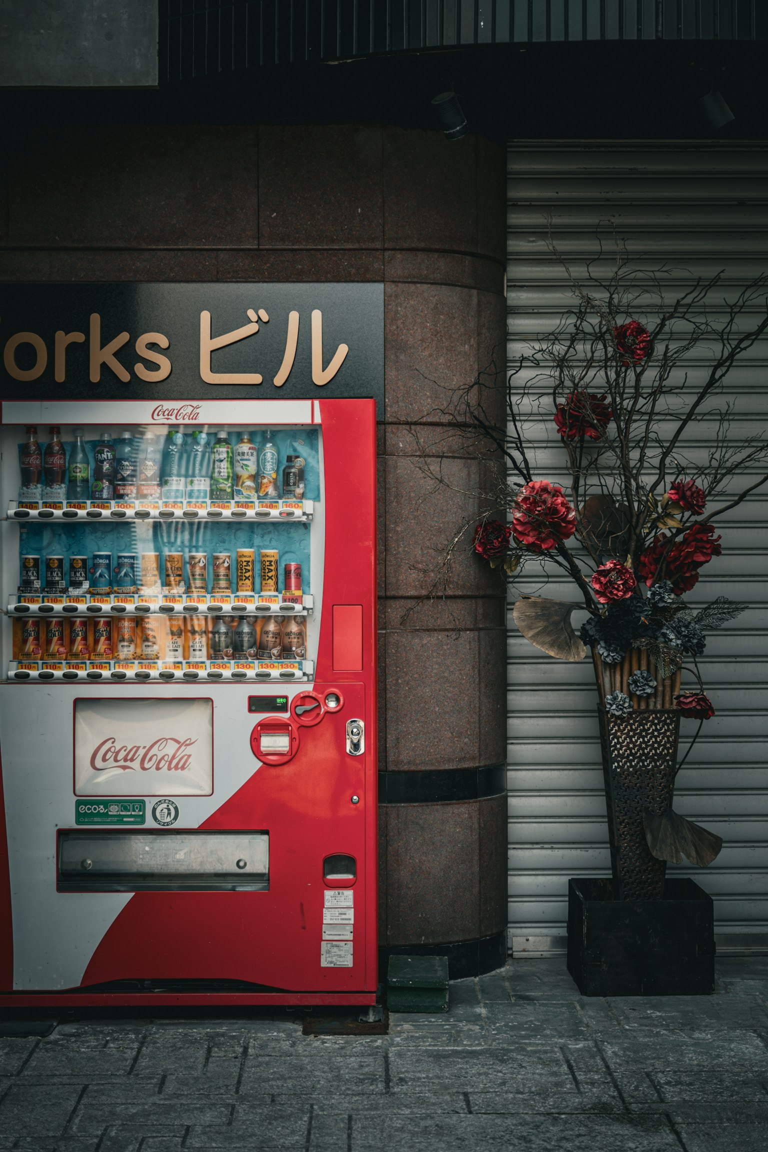 Coin de rue avec un distributeur automatique rouge et une décoration florale