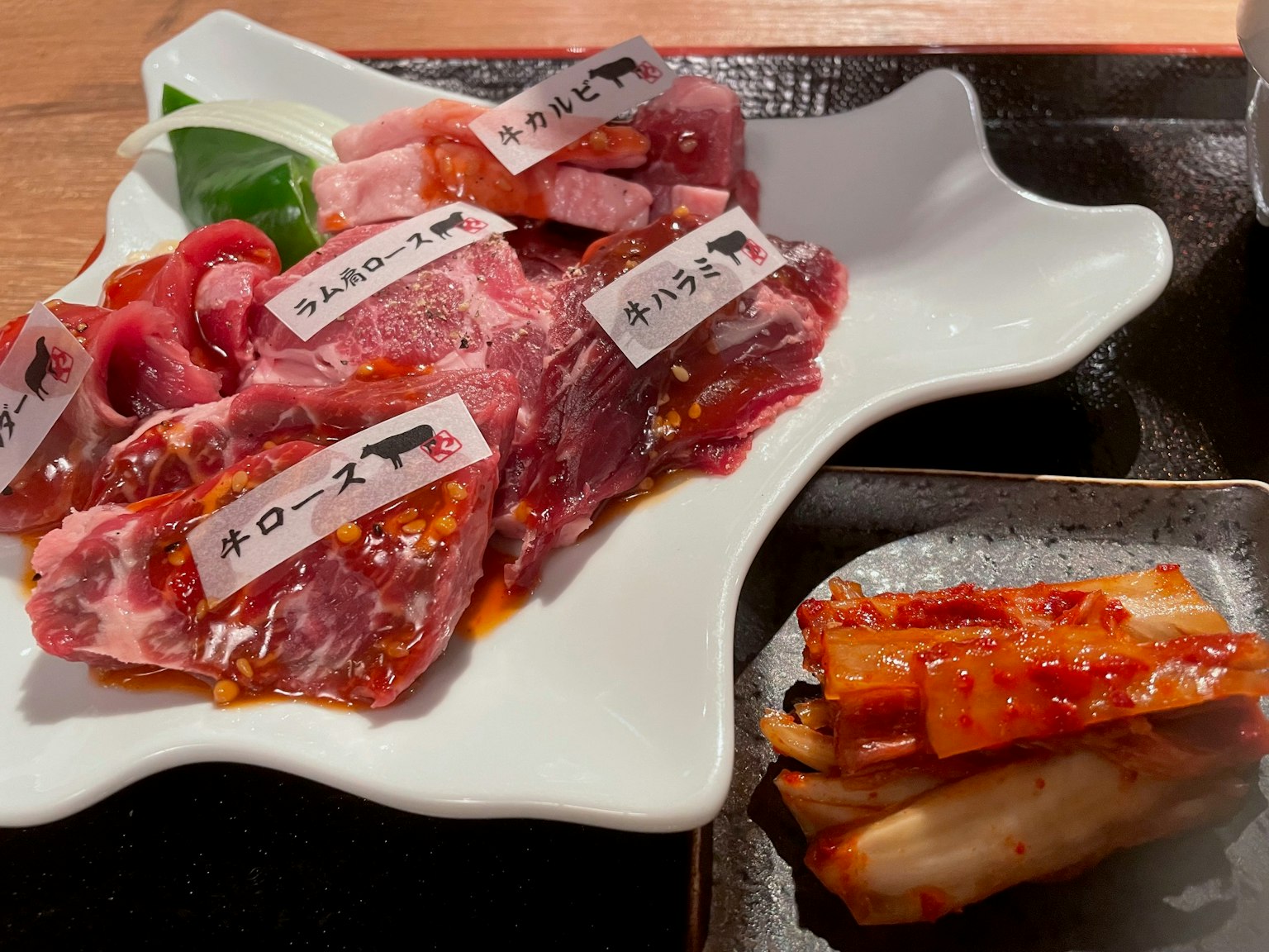 Plateau de tranches de boeuf marbré avec des étiquettes et un accompagnement de kimchi