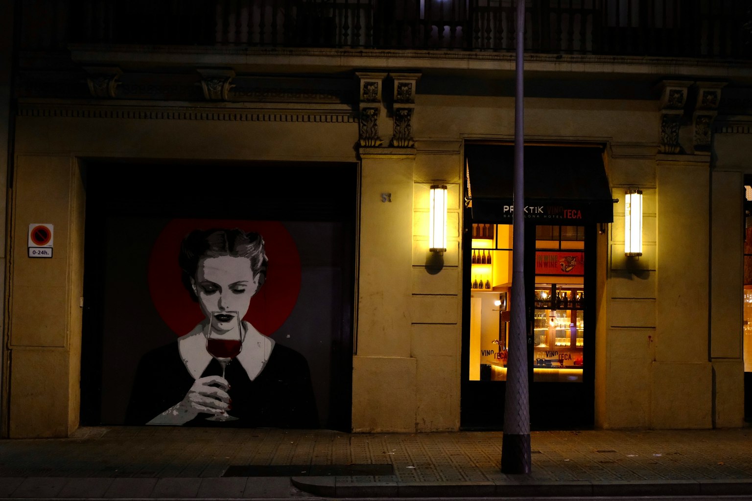 Straßenkunst mit einer Frau, die ein Glas hält, vor einem roten Kreis und einem beleuchteten Schaufenster