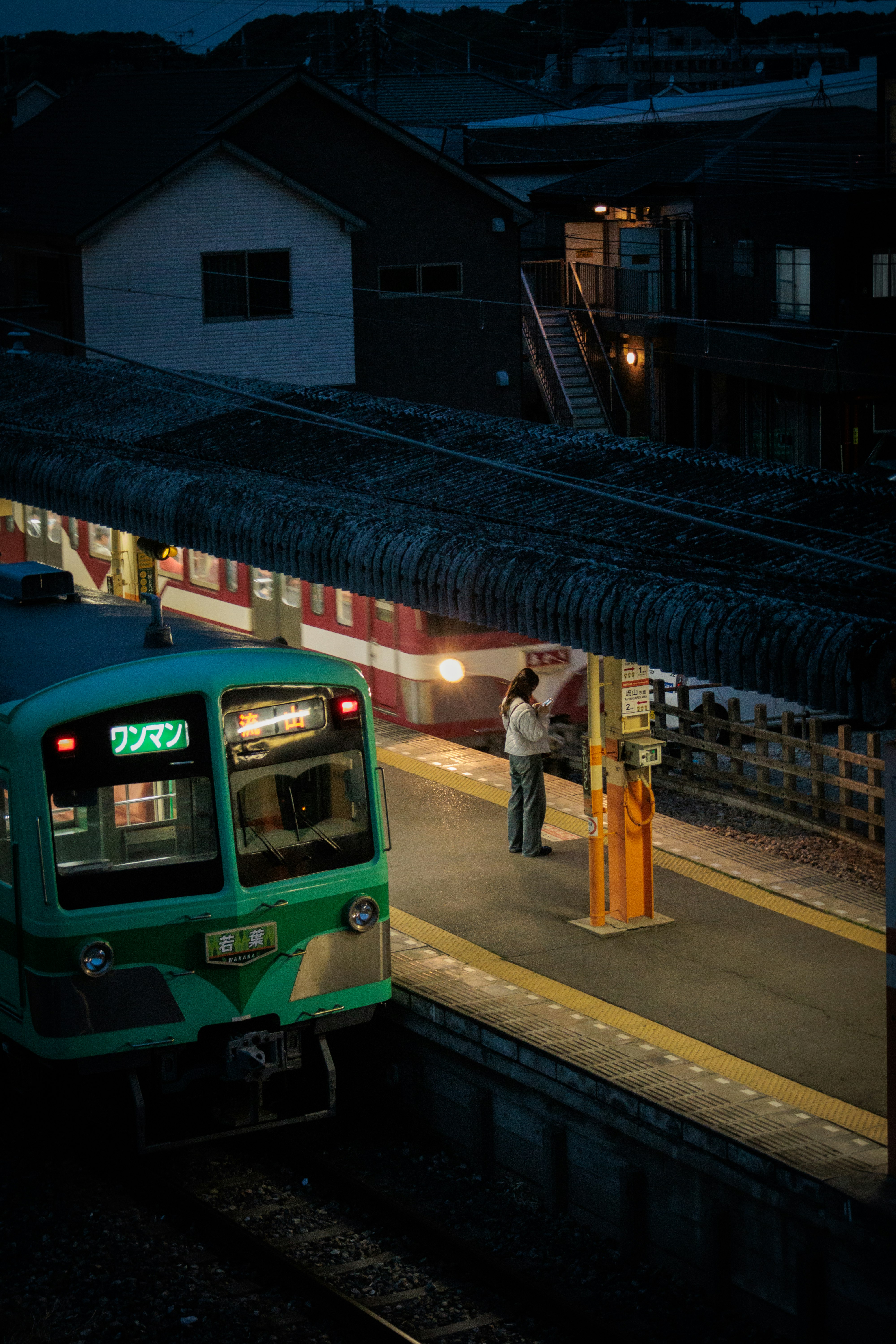 夜晚車站月台停靠的綠色列車與候車人