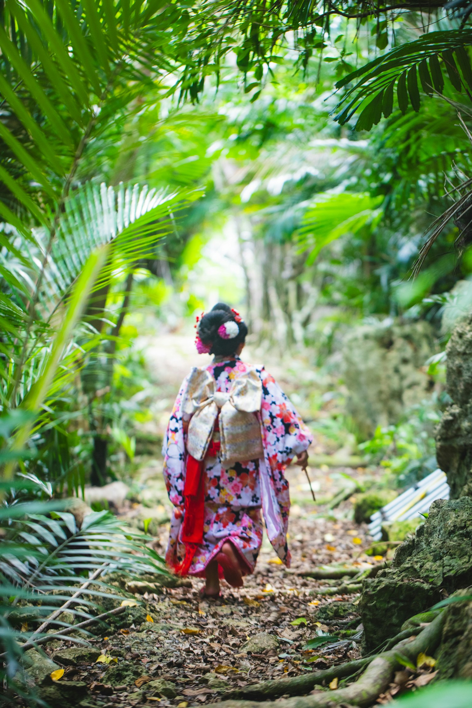 Donna in kimono tradizionale che cammina lungo un sentiero lussureggiante nella giungla