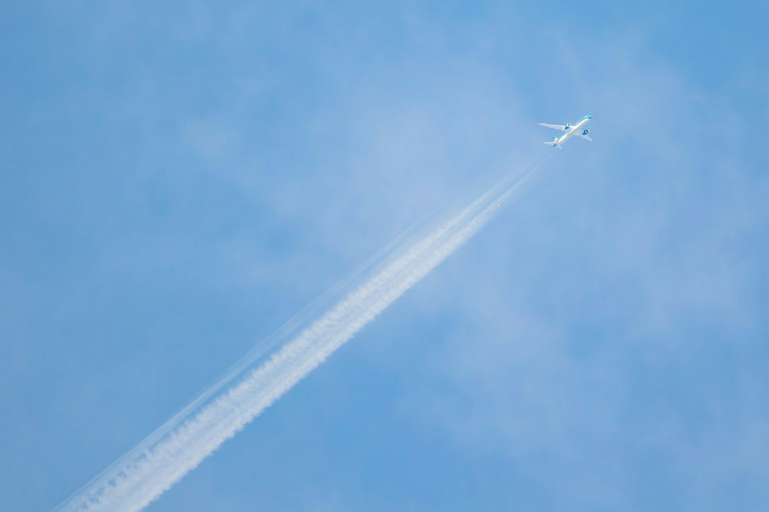 Avión volando en un cielo azul con estela