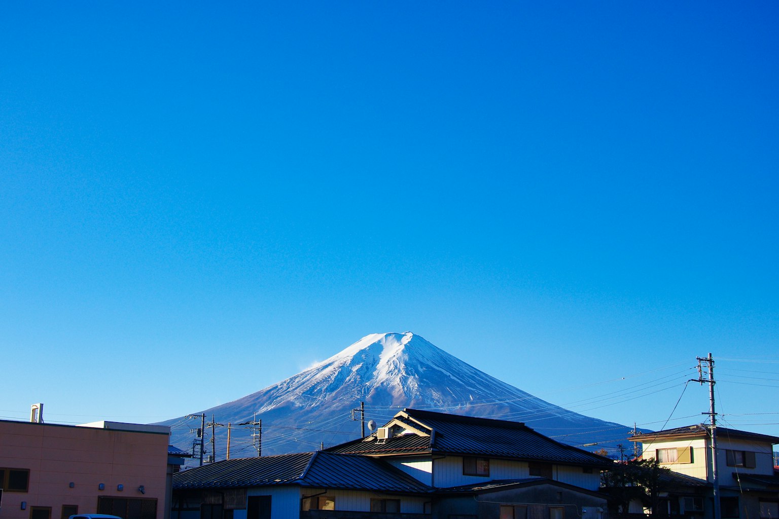 Mont Fuji enneigé sous un ciel bleu clair avec des bâtiments environnants