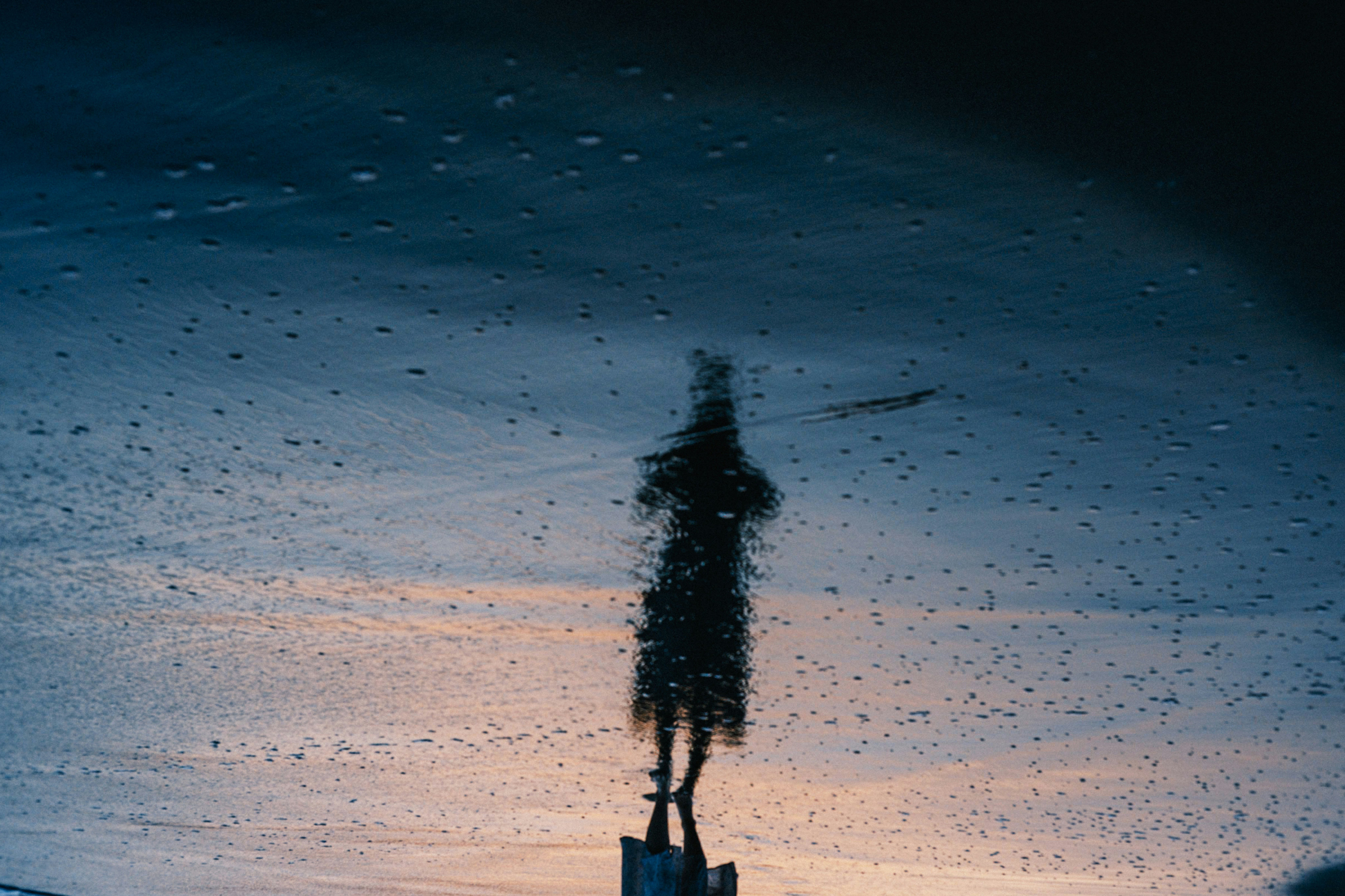 silhouette walking on a beach at dusk