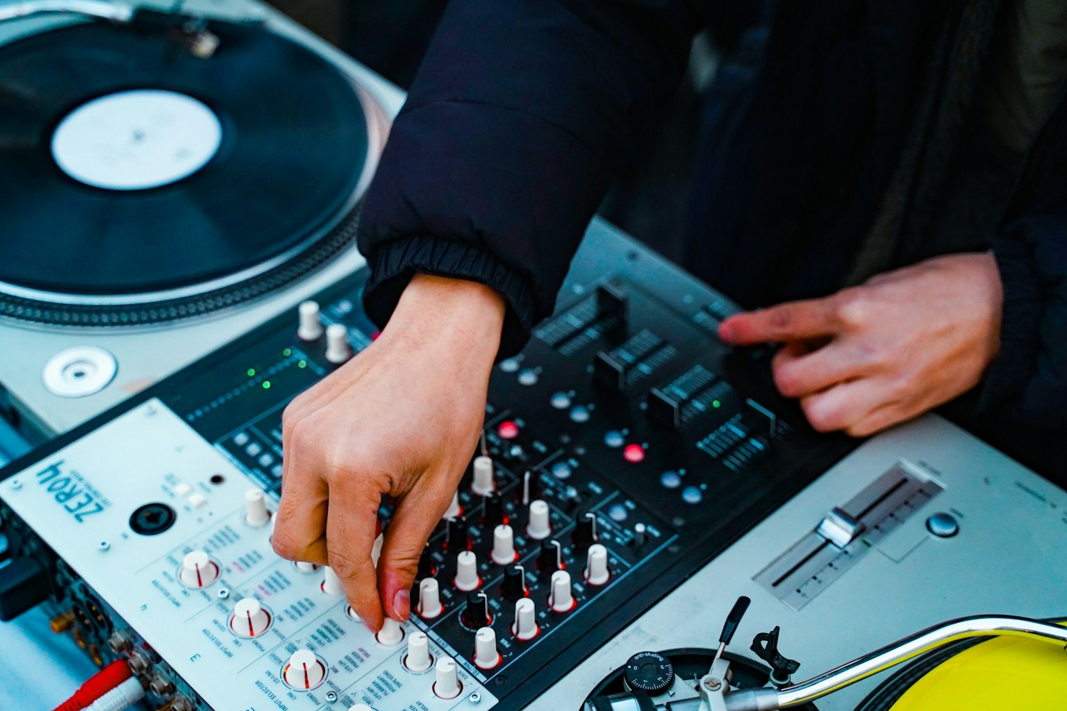Cận cảnh tay DJ điều chỉnh mixer và turntable