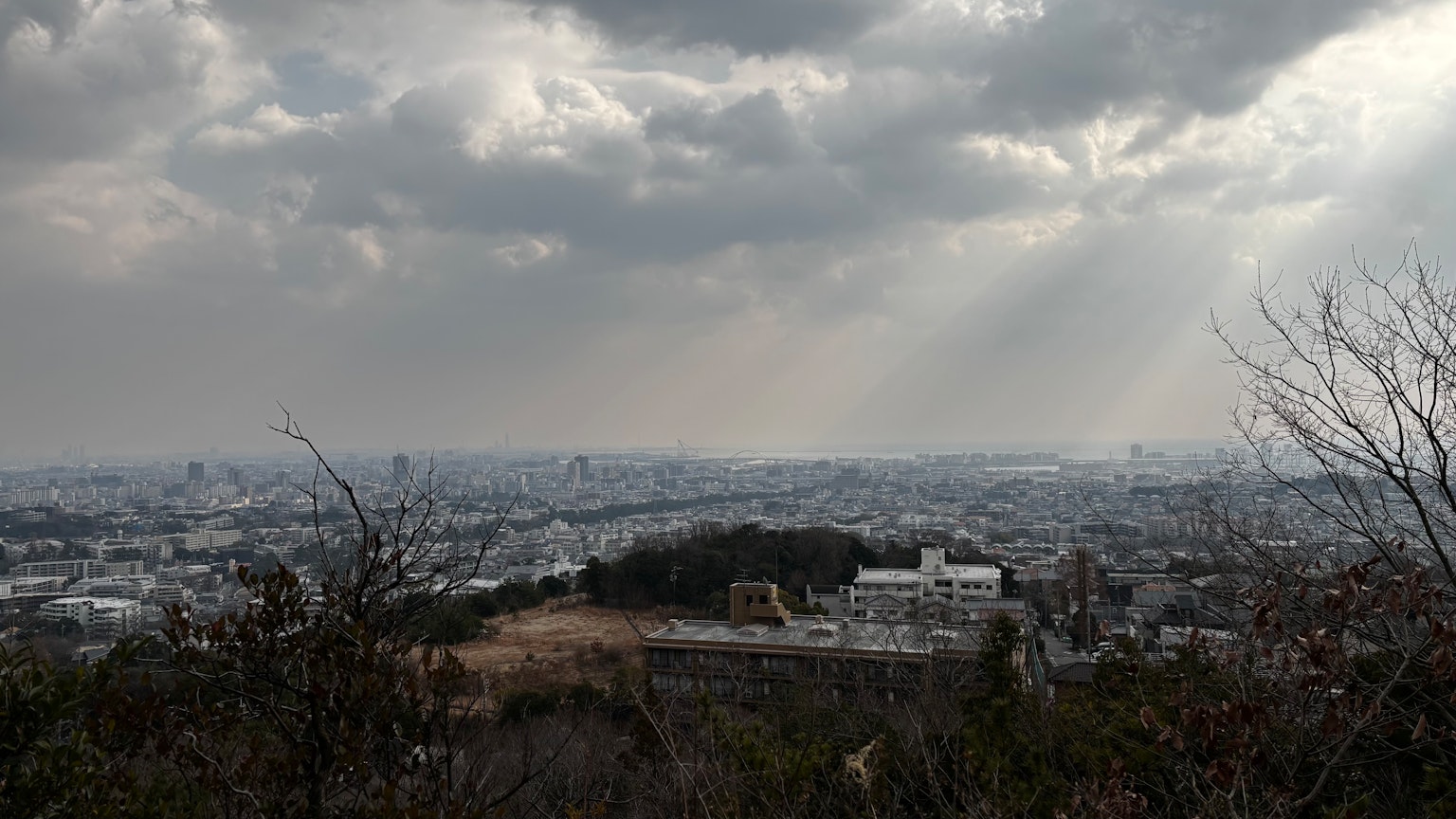 Urban landscape under a cloudy sky with silhouettes of mountains