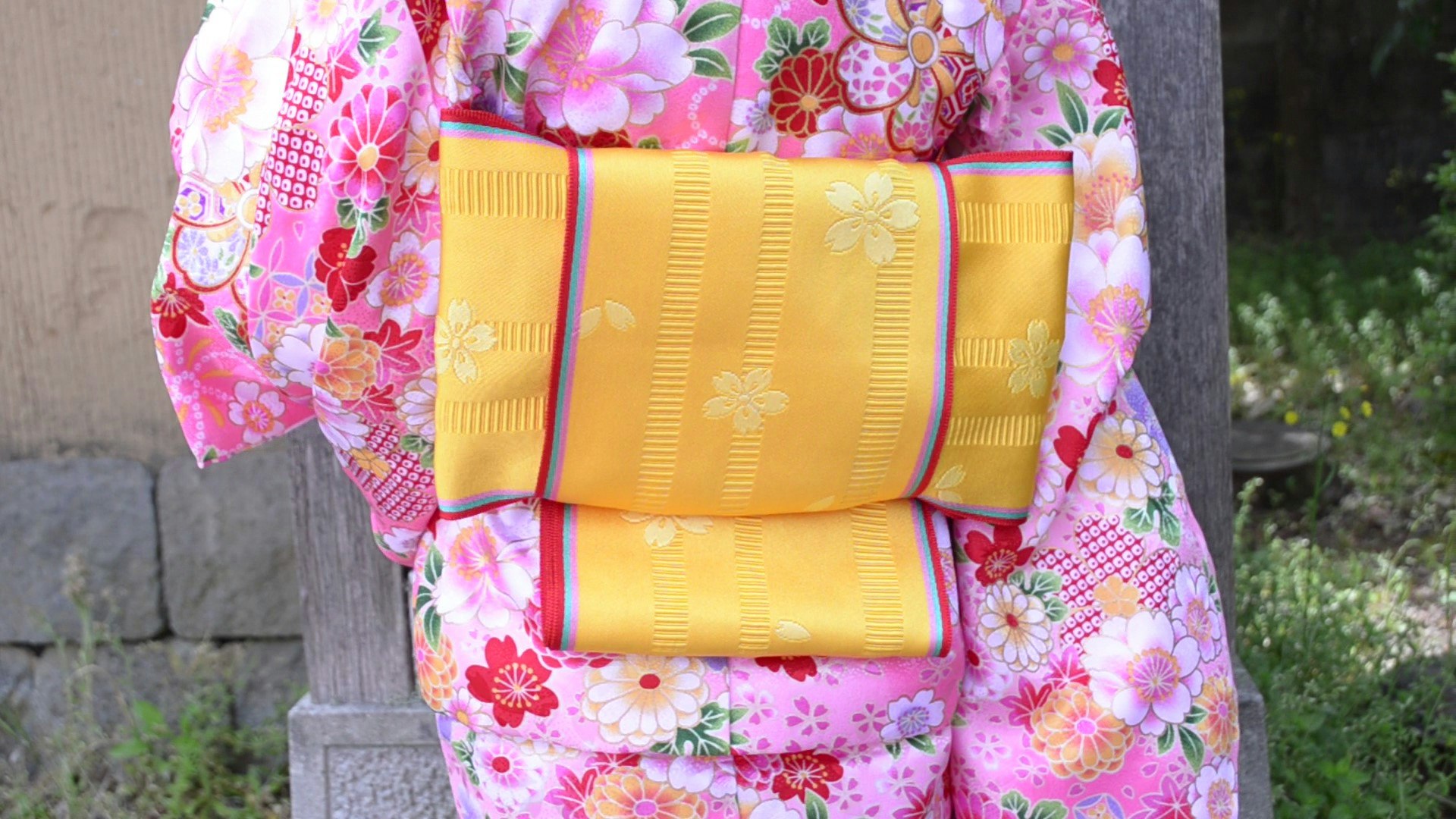 woman in colorful kimono holding a yellow traditional bag, back view
