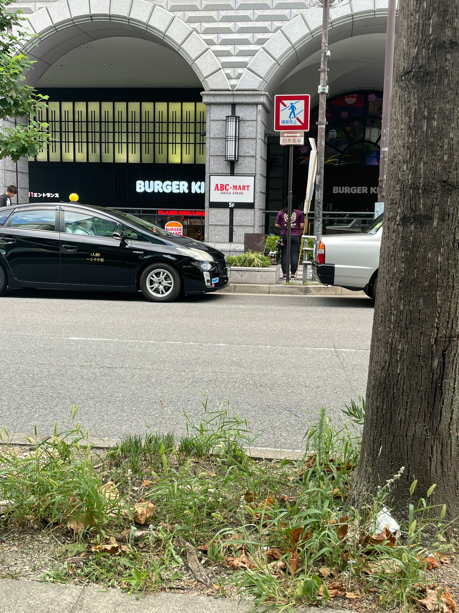 Vista di strada con un'auto nera e un'auto bianca con un'insegna Burger King visibile