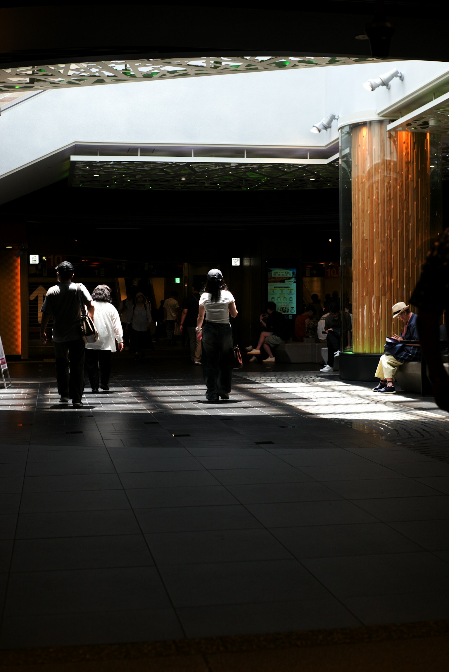 Modern space with bright lighting featuring people walking and wooden columns