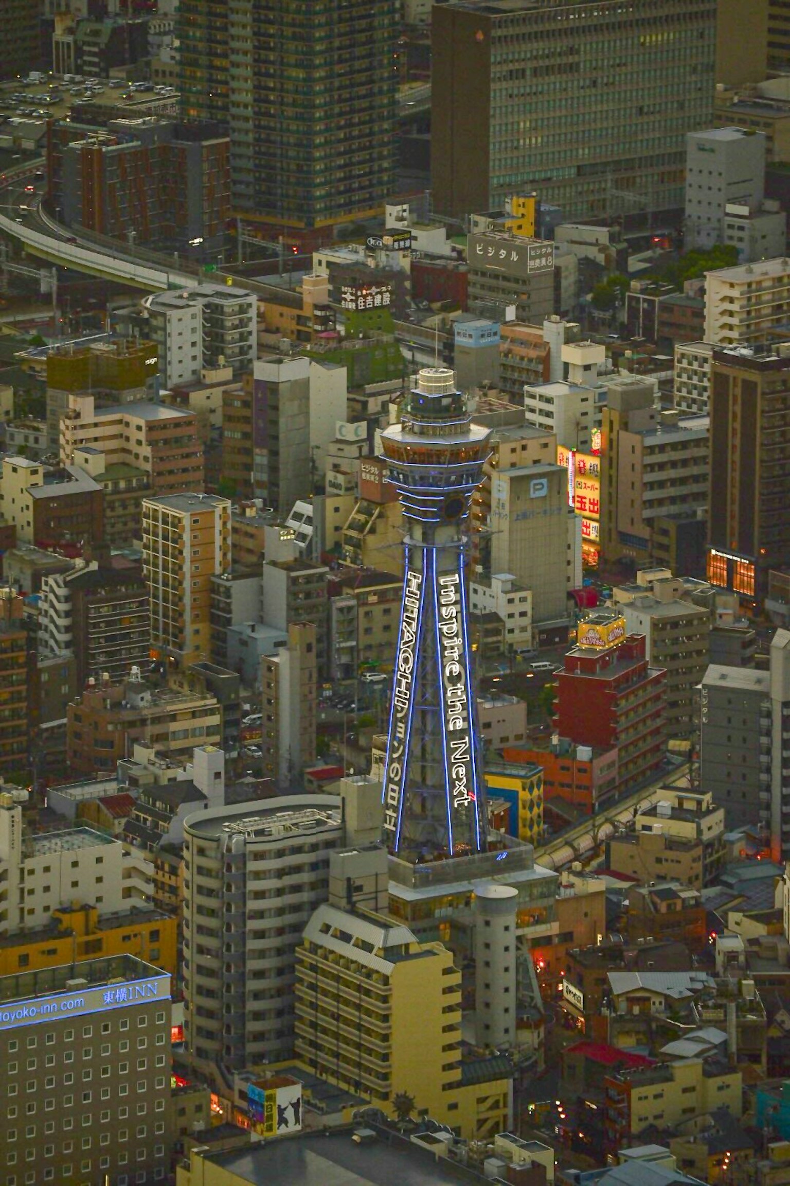 Vista notturna della Torre Tsutenkaku circondata da grattacieli
