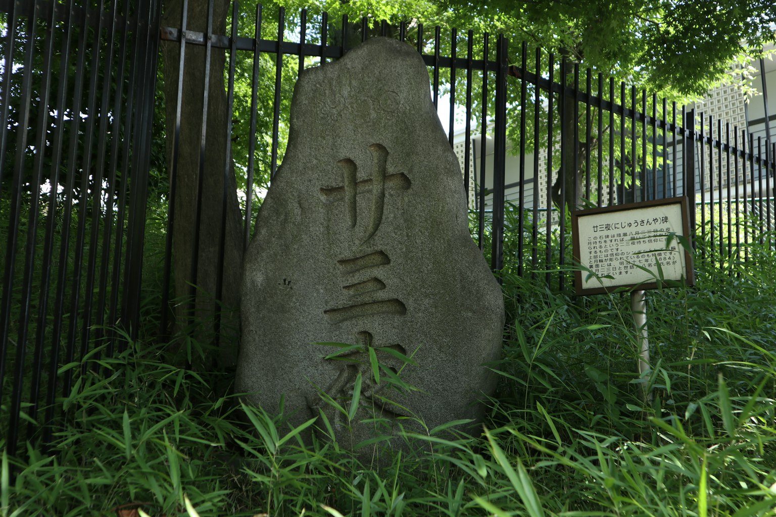 Monumento de piedra con tres caracteres inscritos rodeado de vegetación exuberante