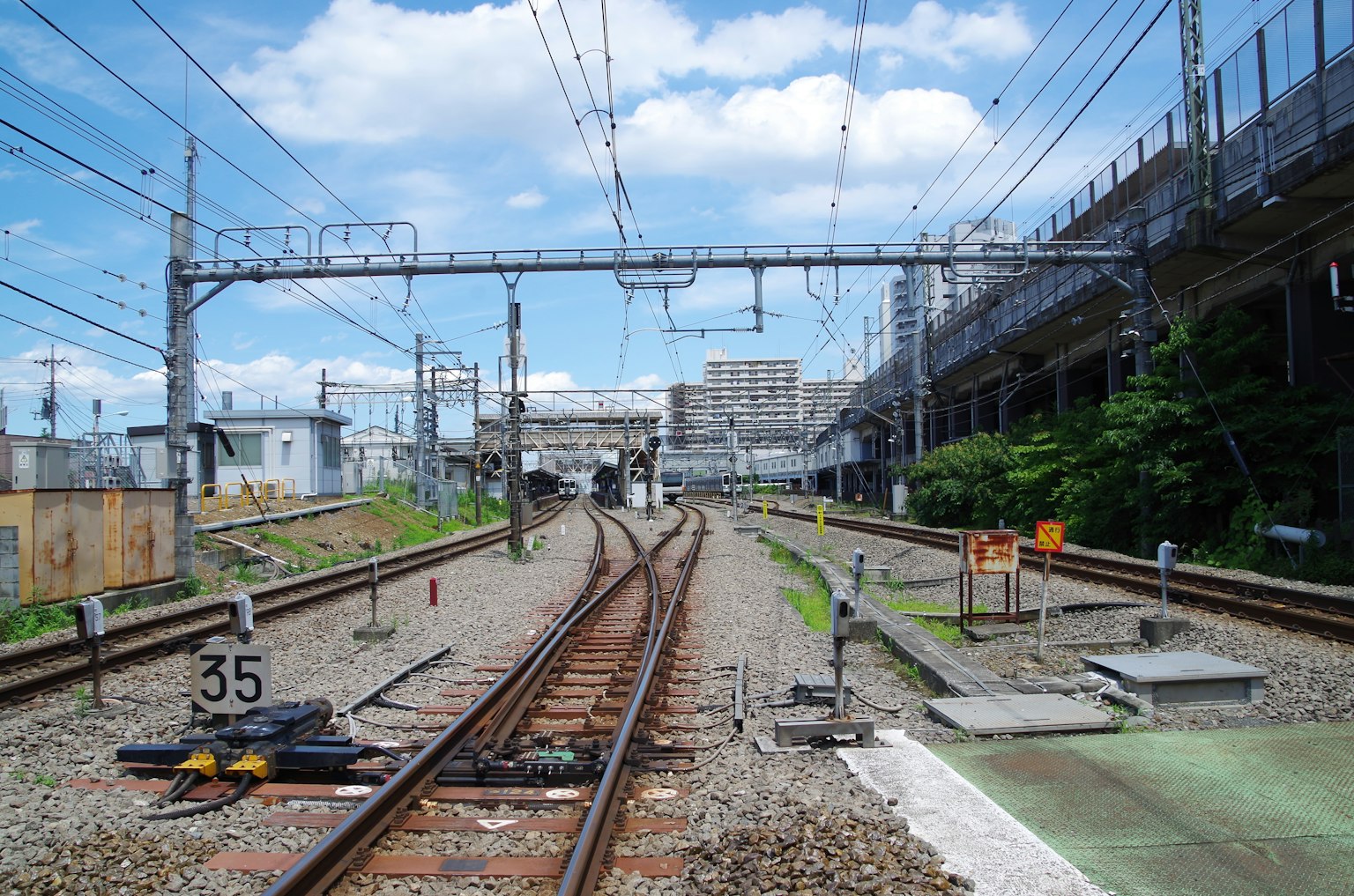 วิวของรางรถไฟที่แยกออกพร้อมกับอาคารและเสาสัญญาณใกล้เคียง