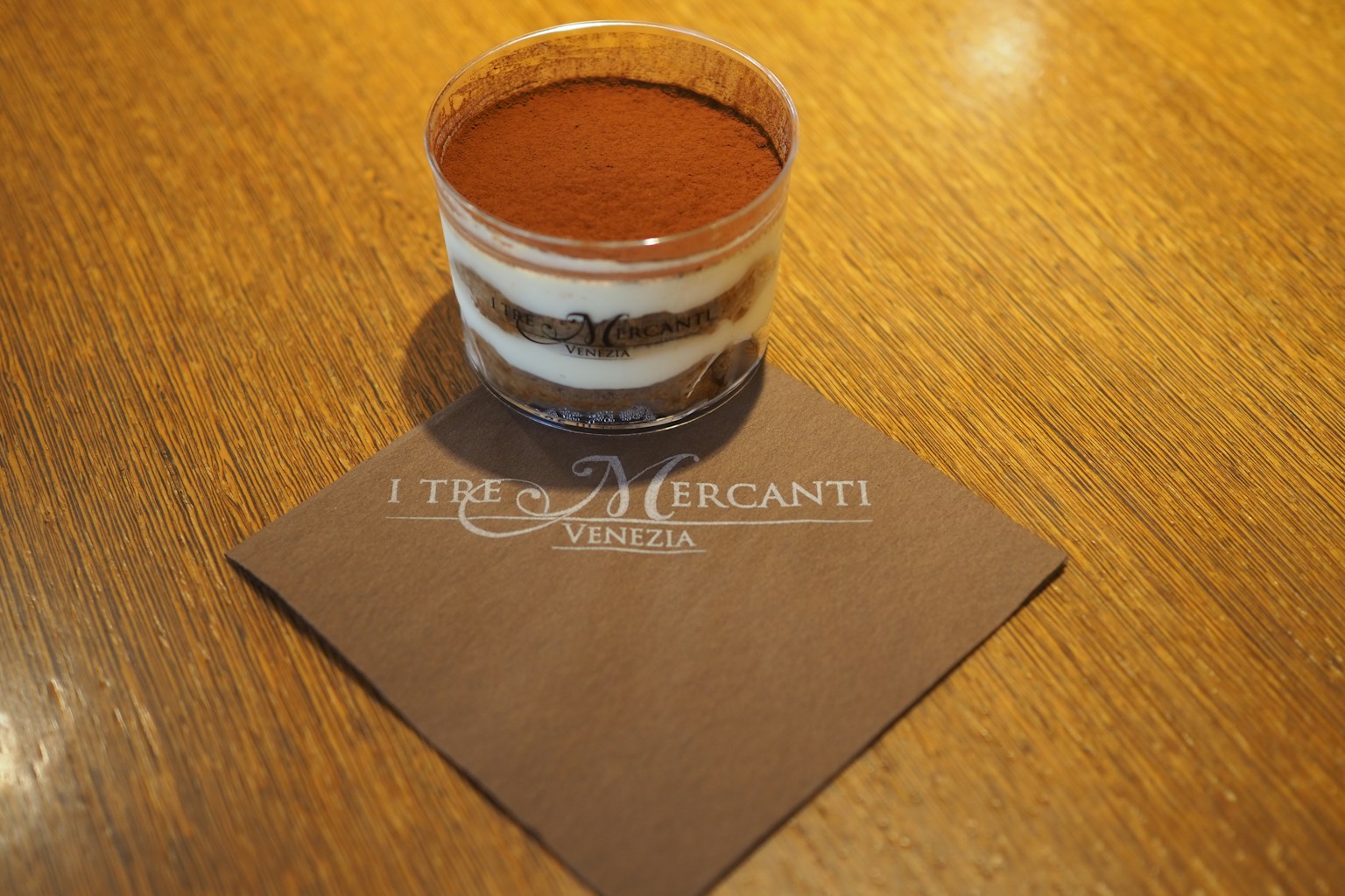 Cangkir tiramisù transparan di atas meja kayu