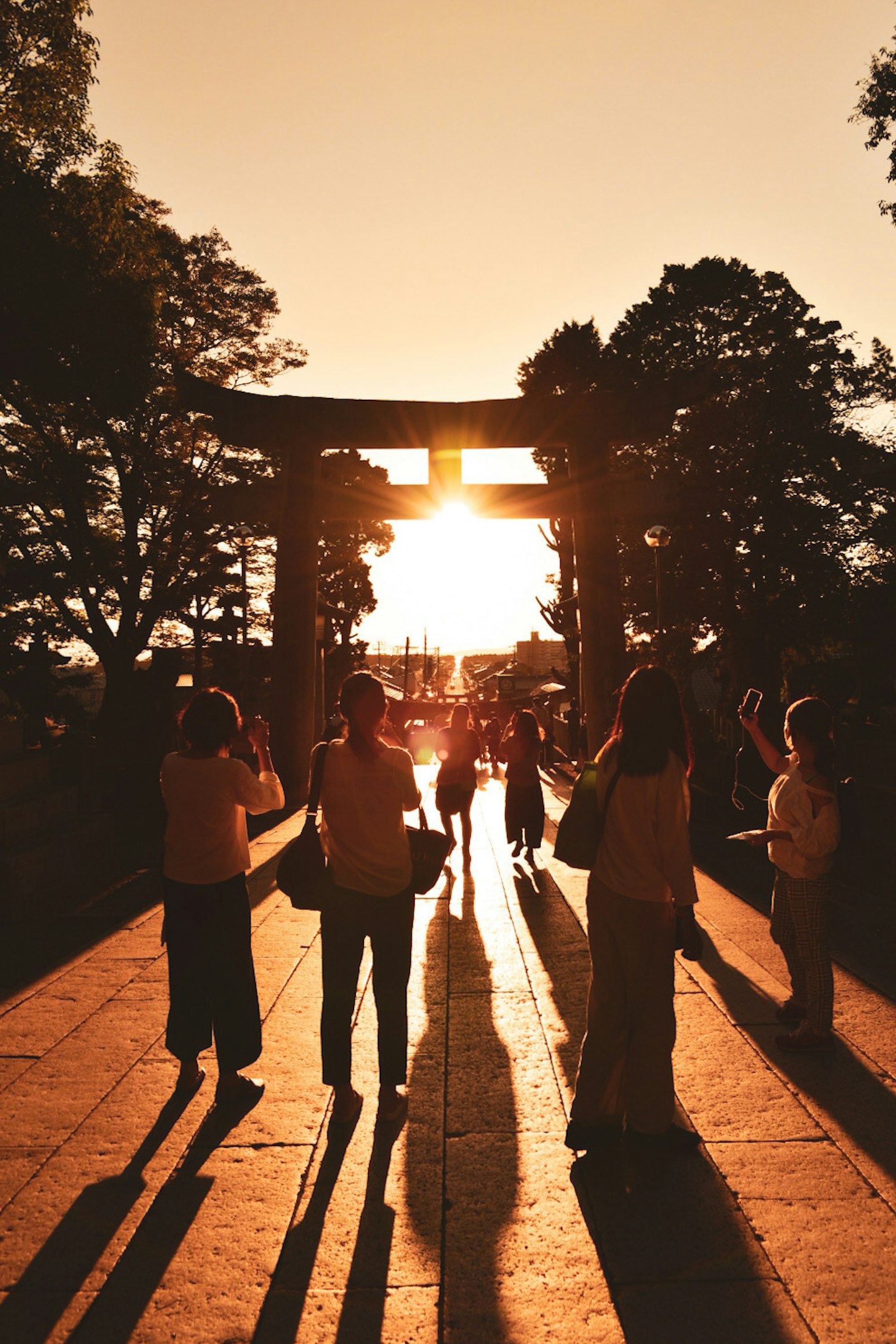 夕日を背景にした鳥居と人々のシルエット