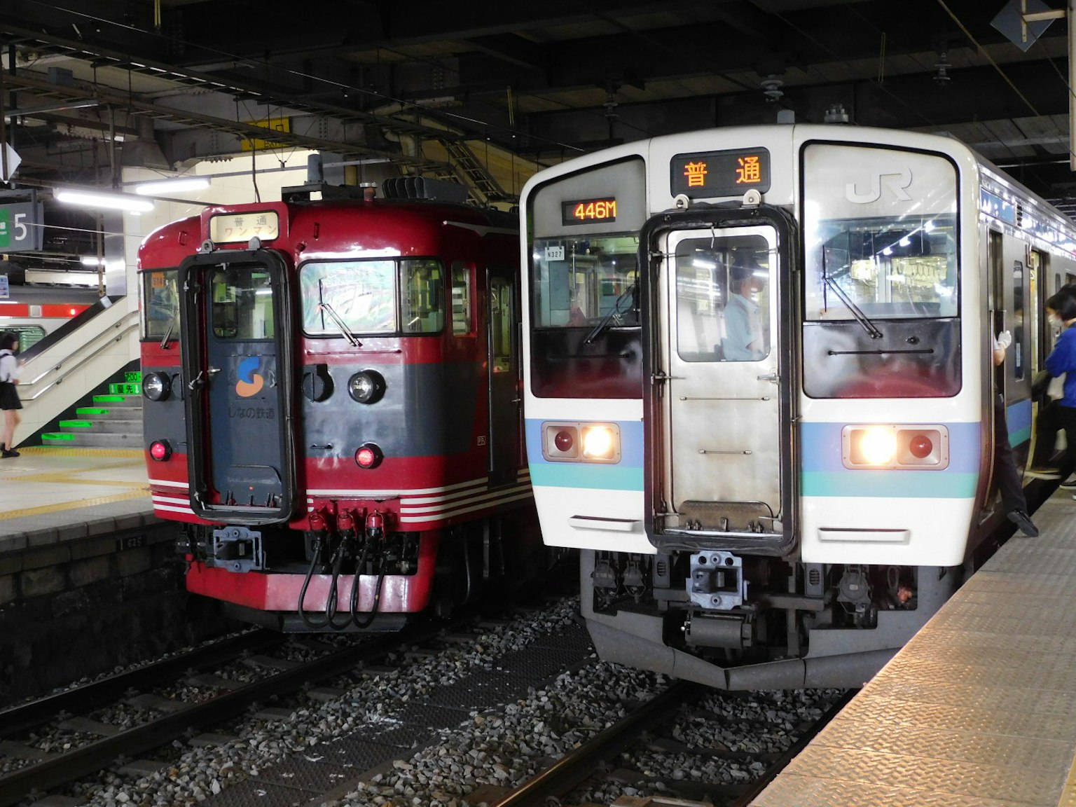 Two trains at the station one red train and one white and blue train