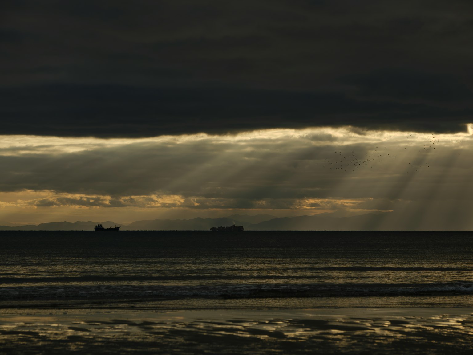 暗い海と雲の中に光の筋が差し込む風景