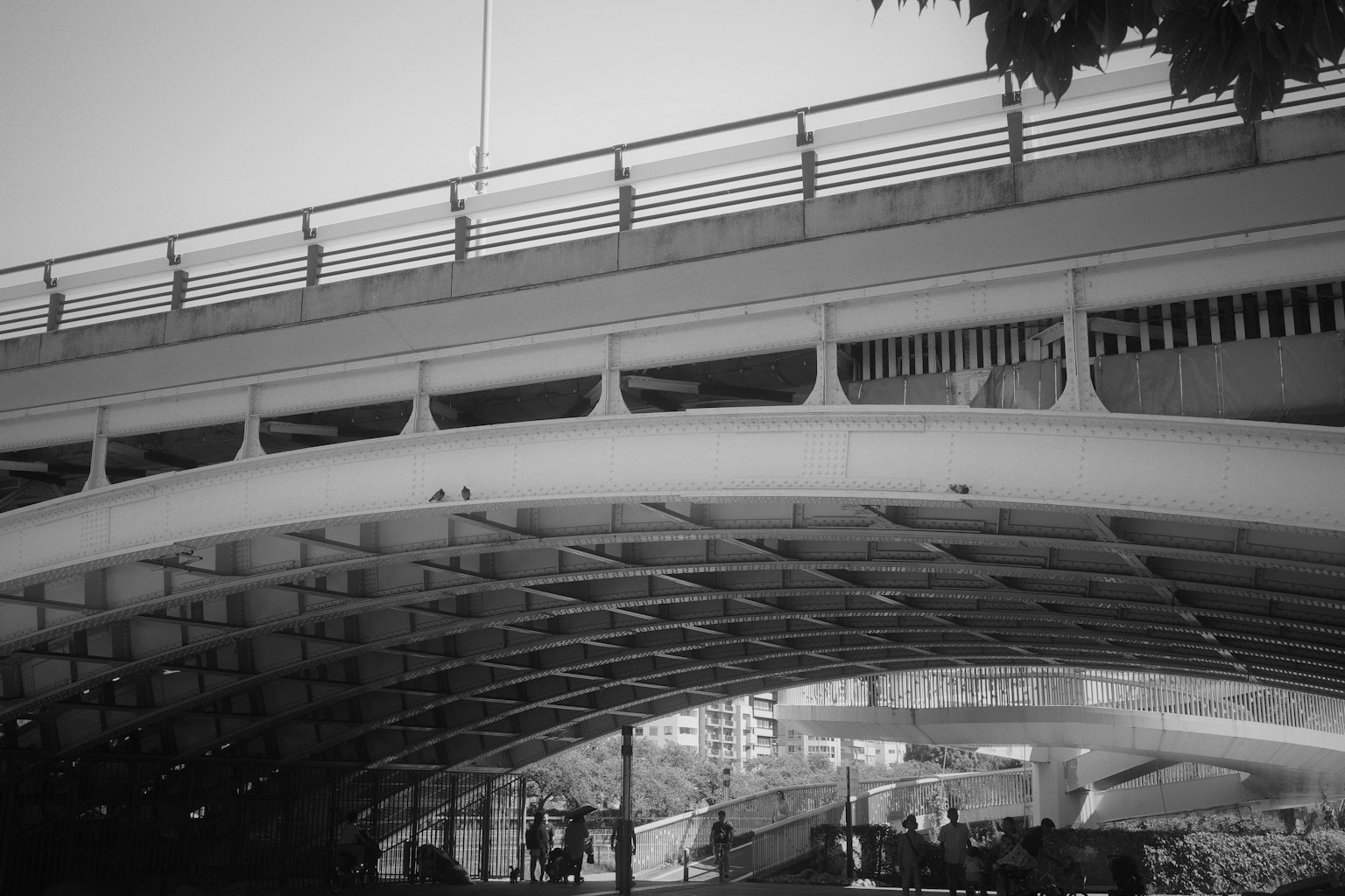 Orang-orang berjalan di bawah jembatan lengkung modern