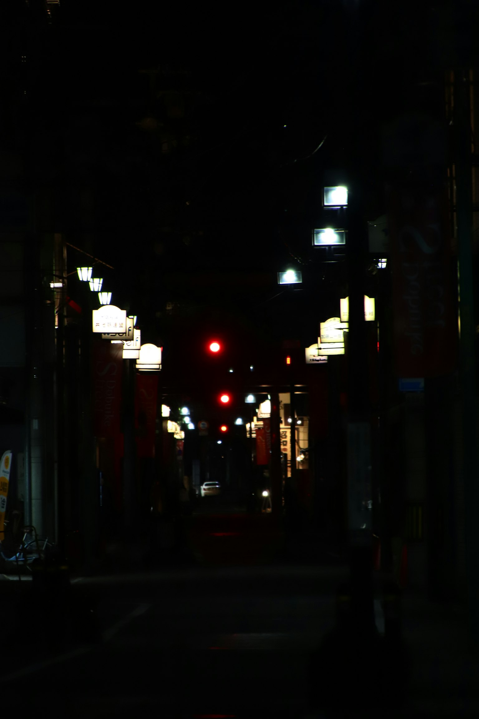 Vicolo scarsamente illuminato con lanterne e un semaforo rosso