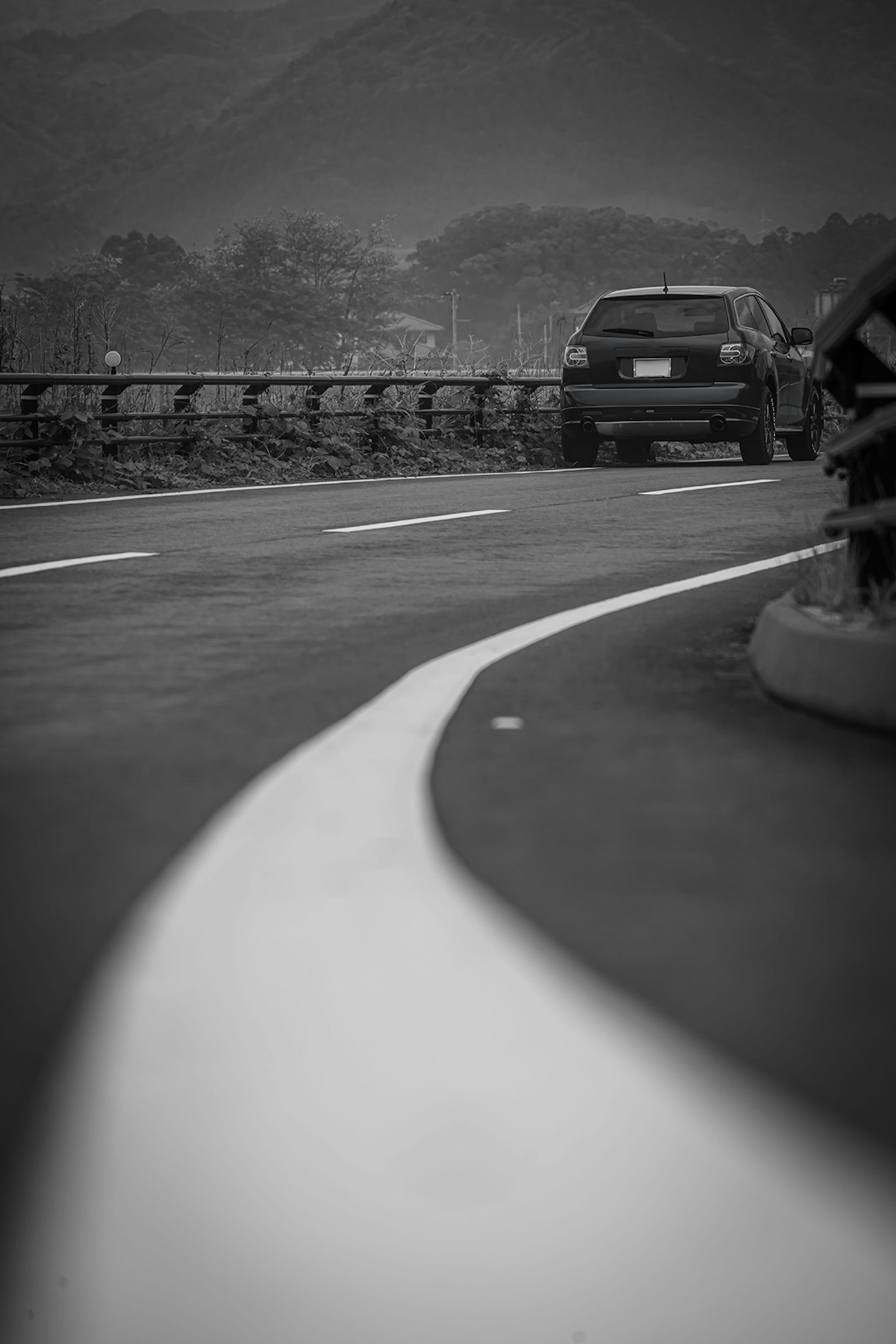Curved white line on the road with a black car nearby