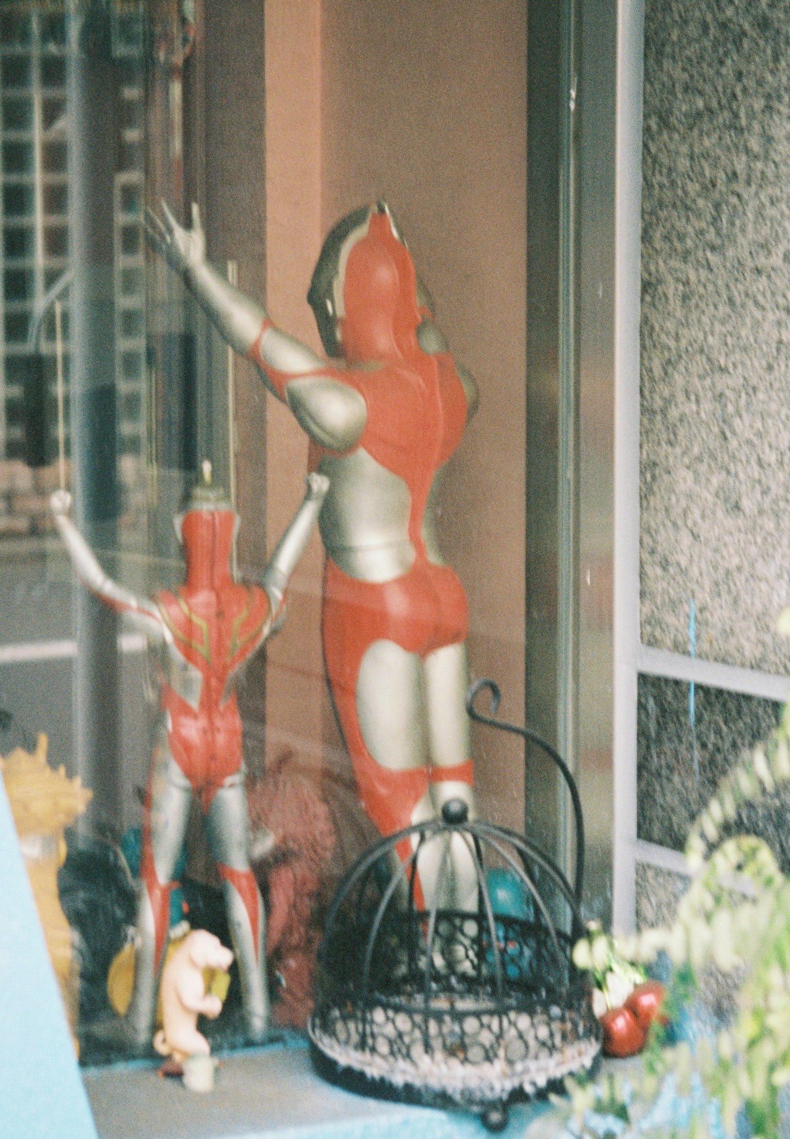 A window display featuring red and silver robot statues with a smaller robot statue behind them