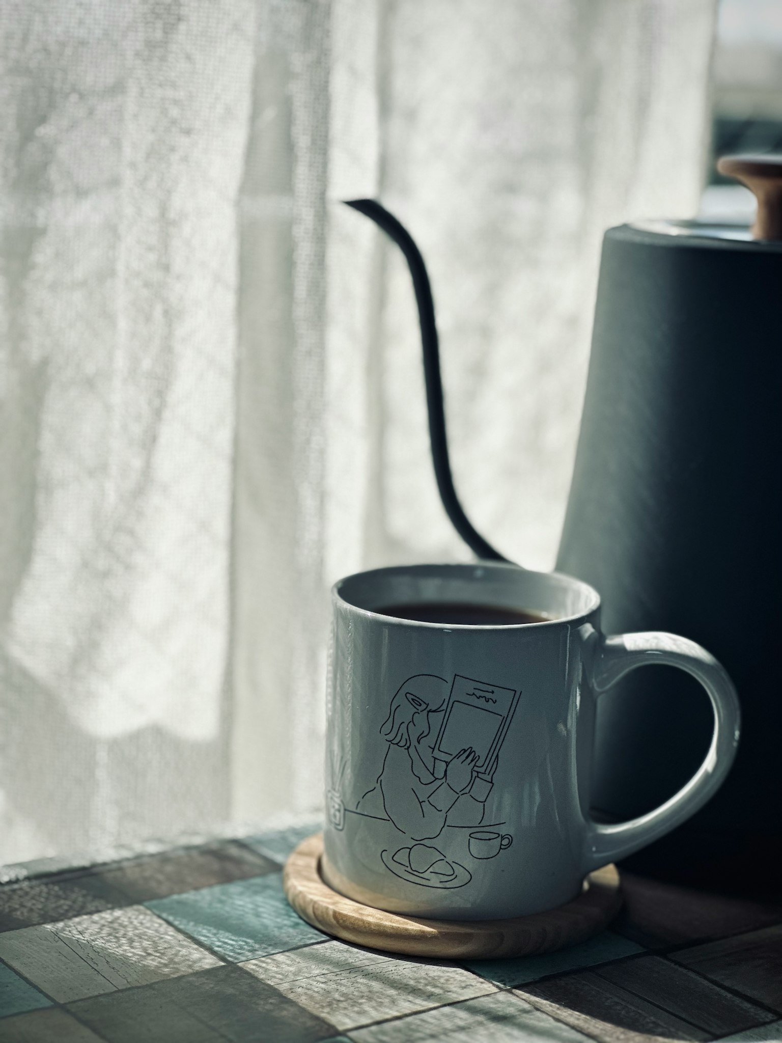 Sebuah cangkir putih penuh kopi di atas meja Cahaya lembut dari jendela menerangi cangkir dan teko kopi