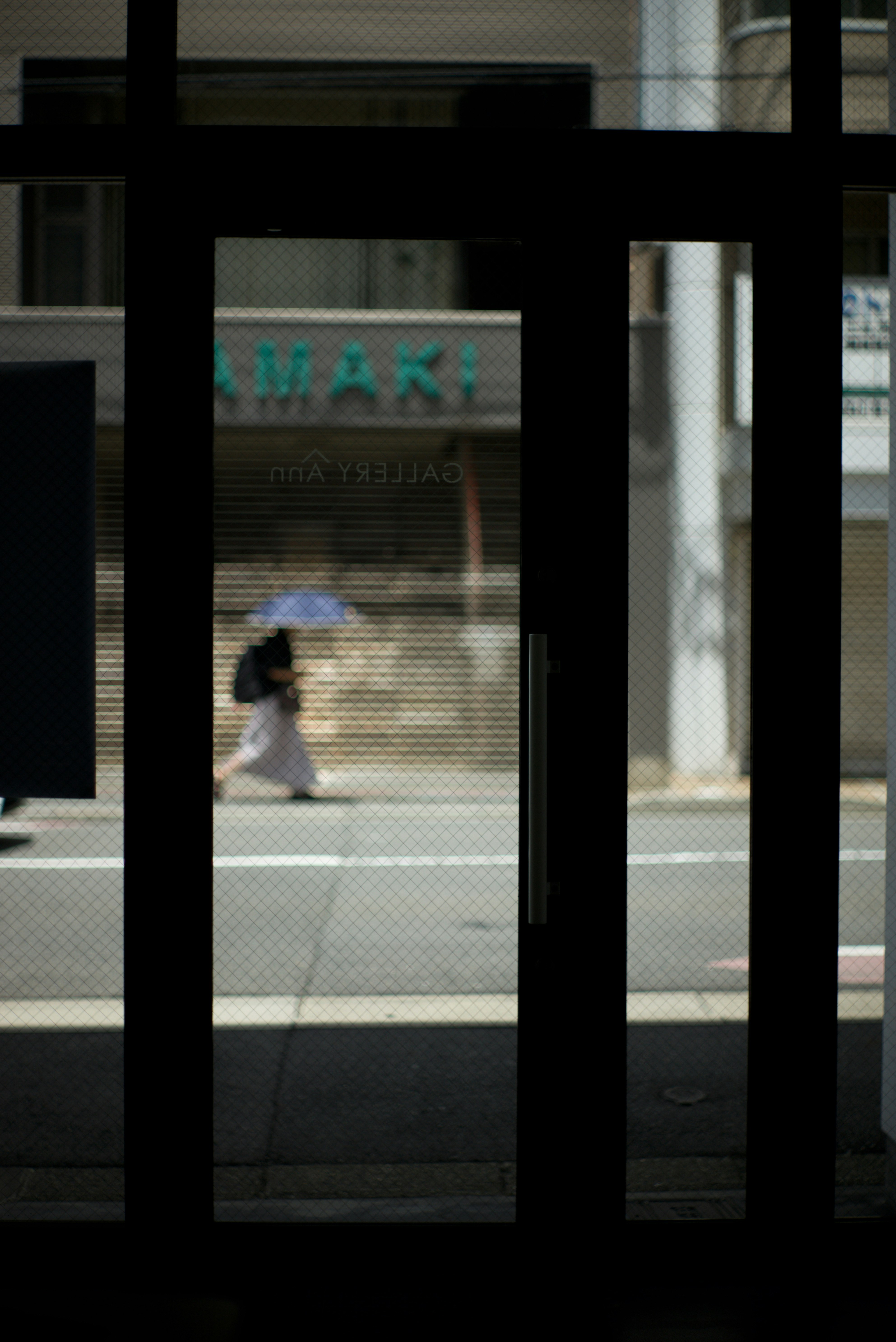 京都小巷里撑伞的人物与“MAKI”店招