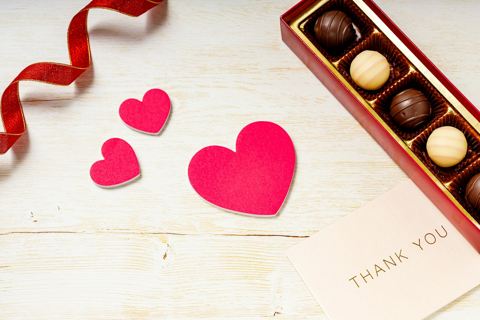 Immagine con decorazioni a forma di cuore rosso e una scatola di cioccolatini