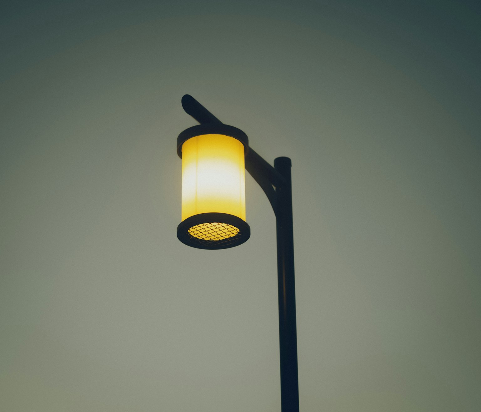 Sebuah lampu jalan dengan desain lampu kuning yang bersinar di atas tiang