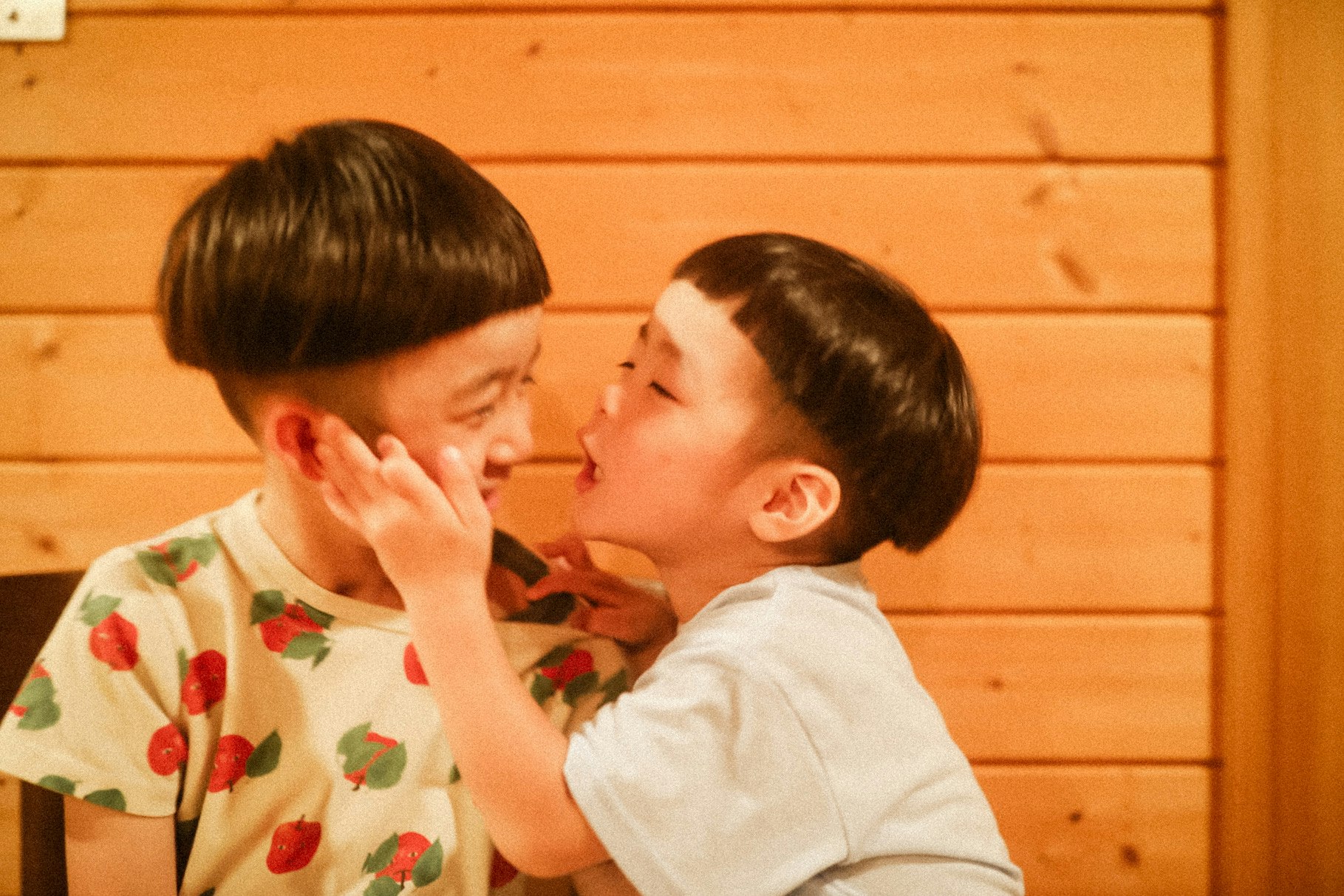 나무 벽 앞에서 다정하게 마주 보는 부모와 아이