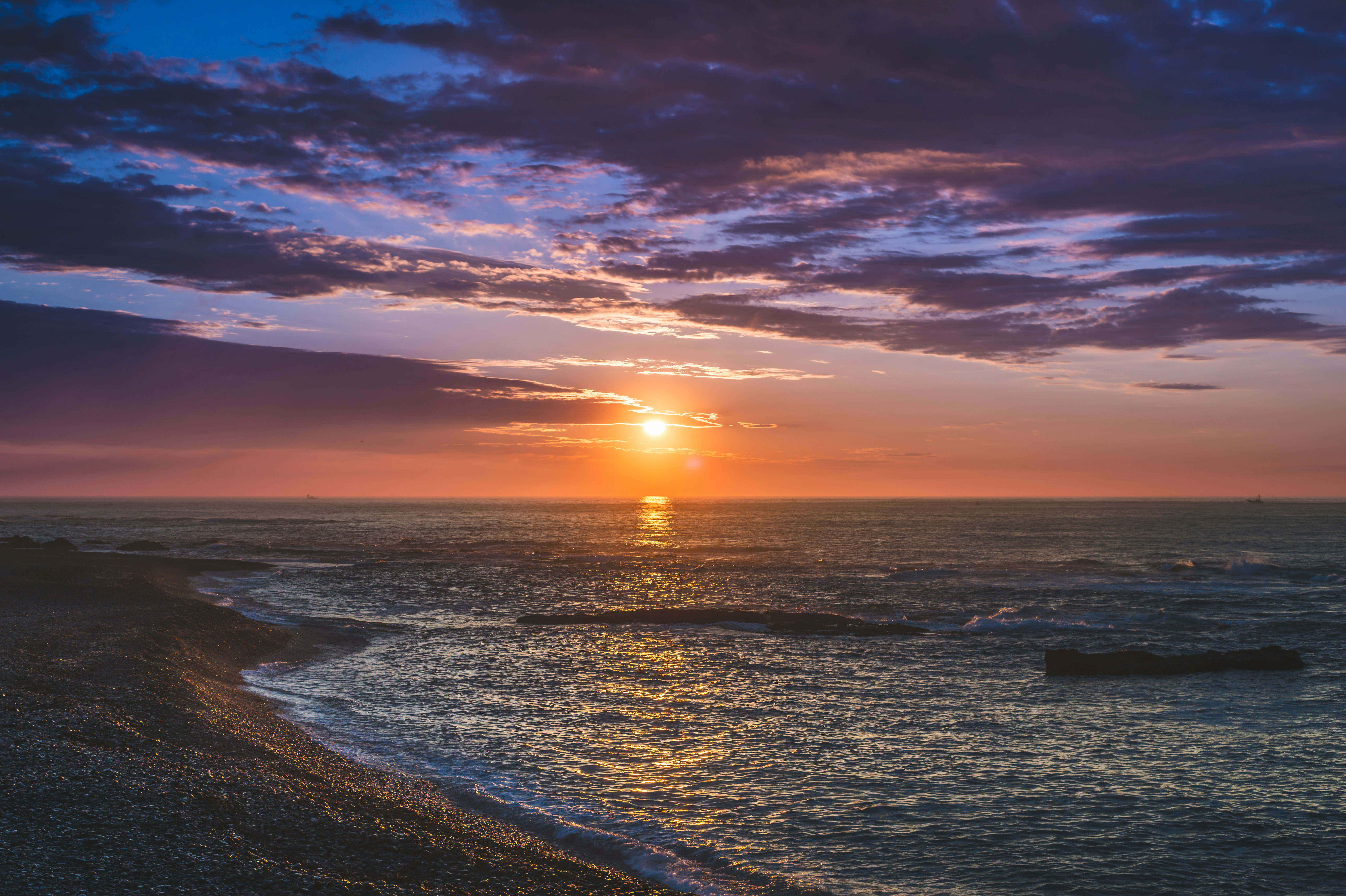 水平線に沈む太陽と夕焼けの海岸の空