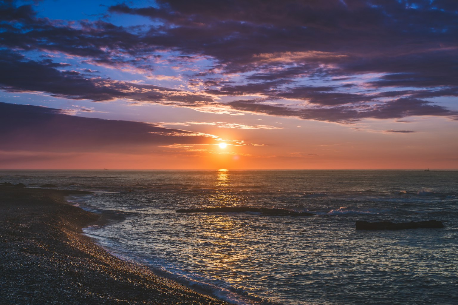 Magnifique coucher de soleil sur l'océan avec des nuages violets et des vagues douces