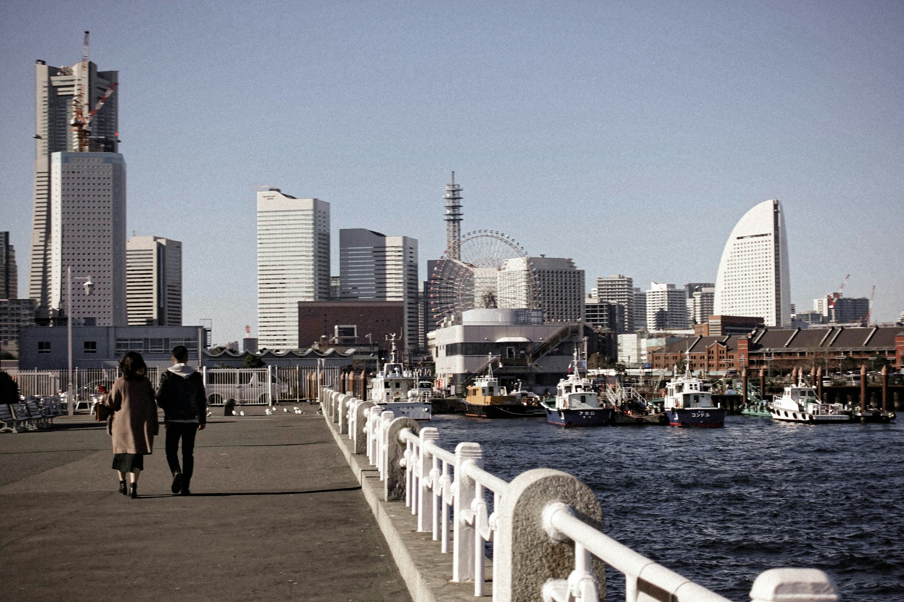 横浜の海沿い遊歩道を歩く二人のカップルの風景