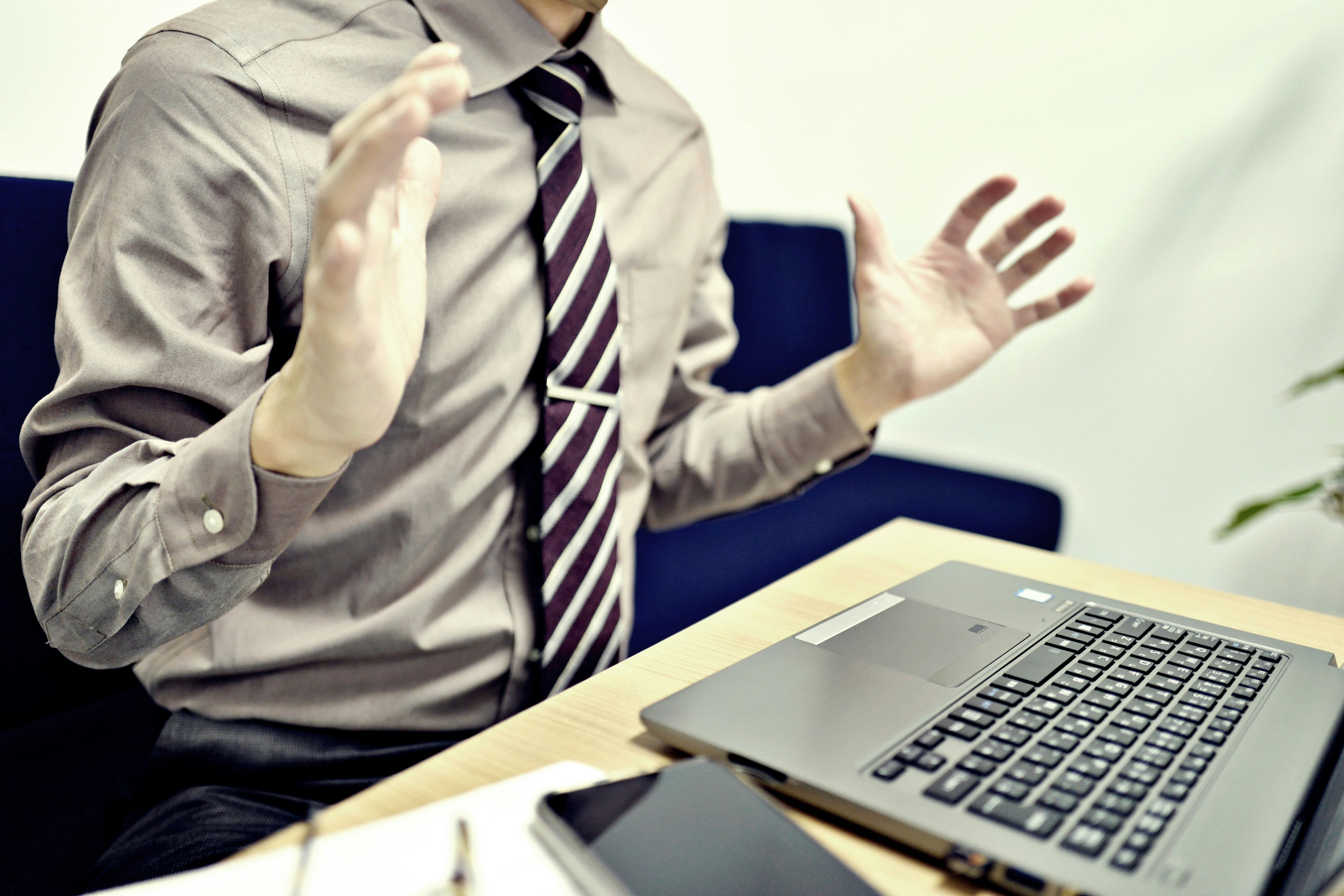 businessman gesturing in an office in front of a laptop