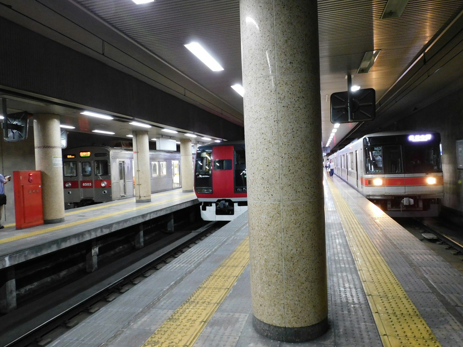 地鐵站台上停著一列紅色列車和一列白色列車