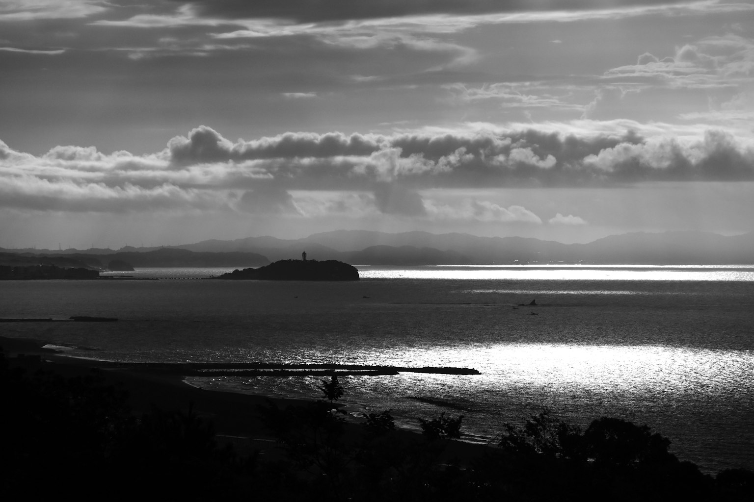 Black and white seascape featuring an island and a lighthouse