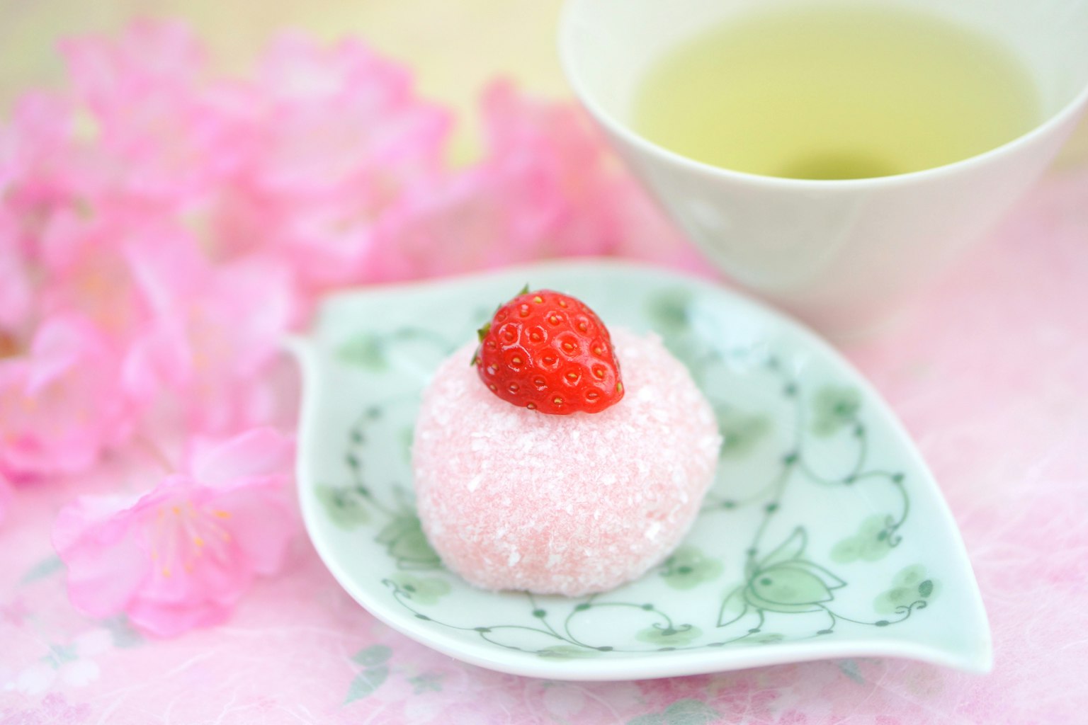 Bánh ngọt Nhật Bản với dâu tây trên đĩa lá và trà xanh