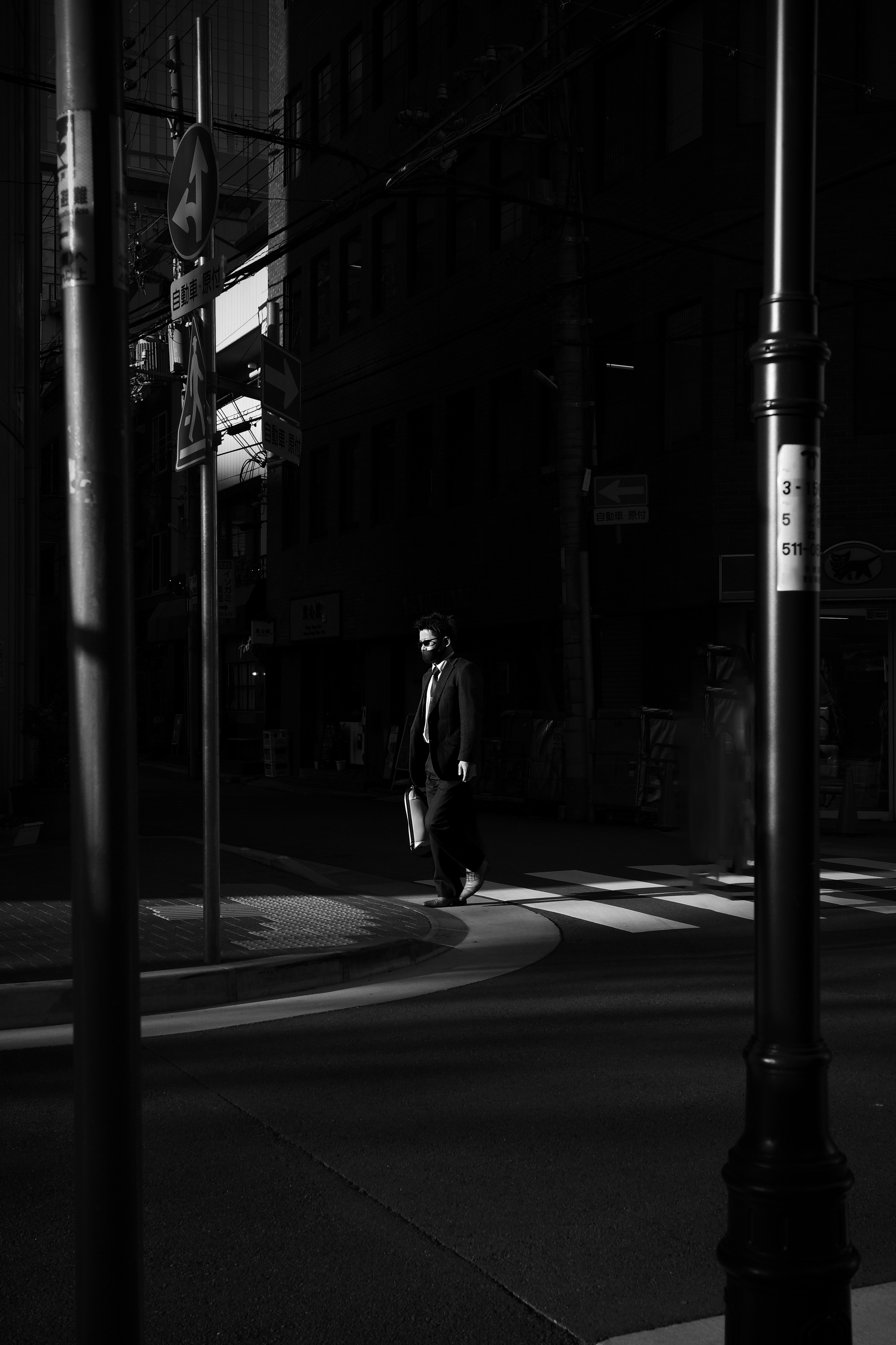路地の光と影の中を歩く人物