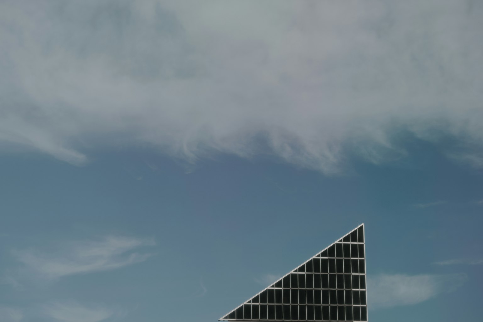 Edificio triangolare moderno parzialmente visibile contro un cielo blu