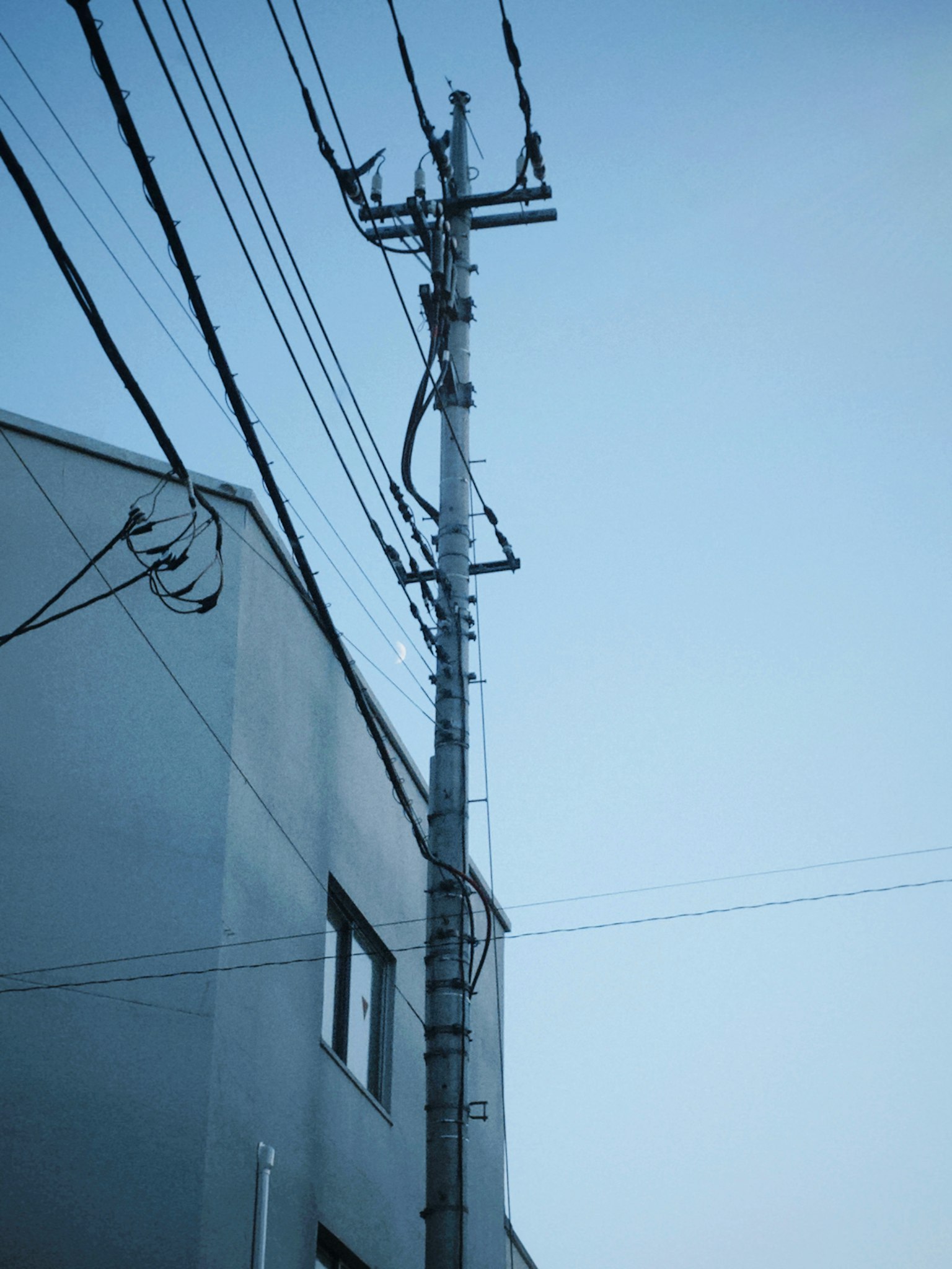Poste eléctrico y líneas eléctricas bajo un cielo azul