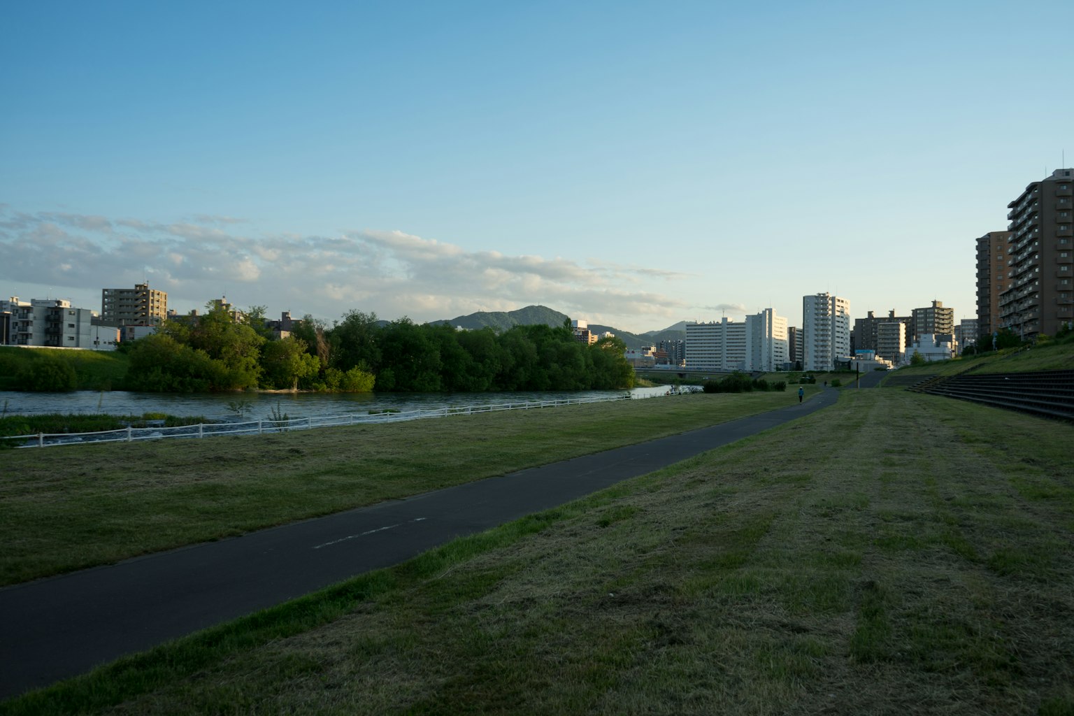 Vue pittoresque d'un parc le long d'une rivière avec des bâtiments en arrière-plan