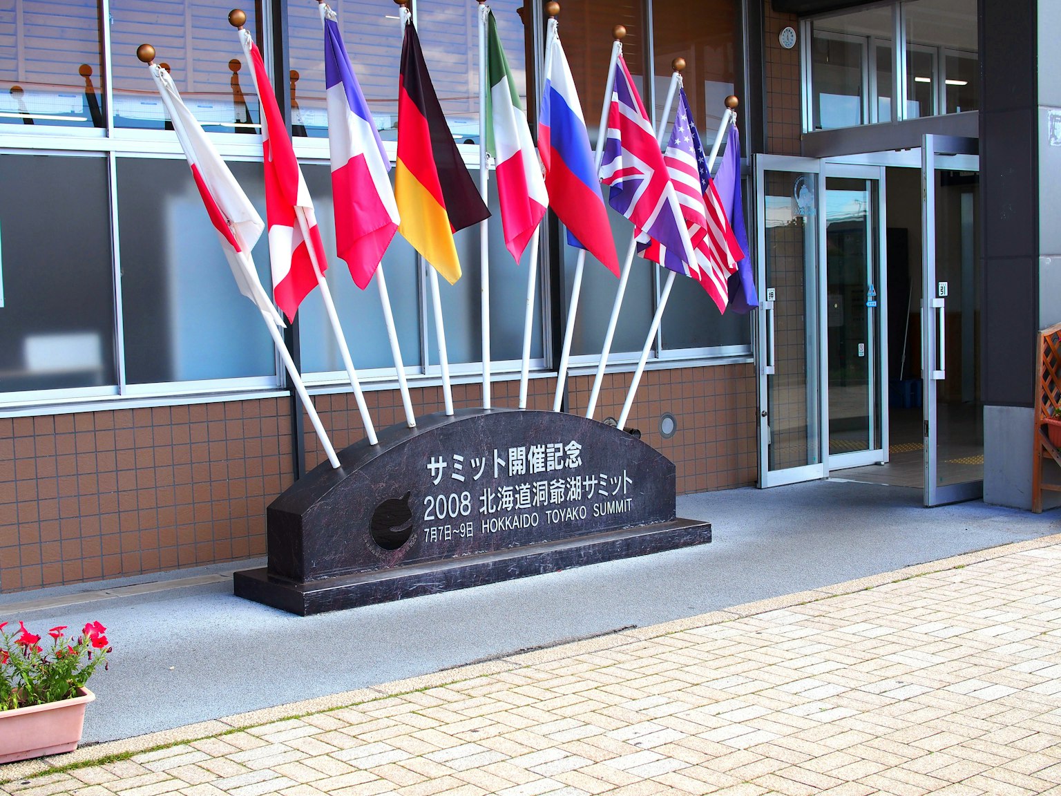 Steinmonument am Eingang eines Gebäudes mit internationalen Flaggen