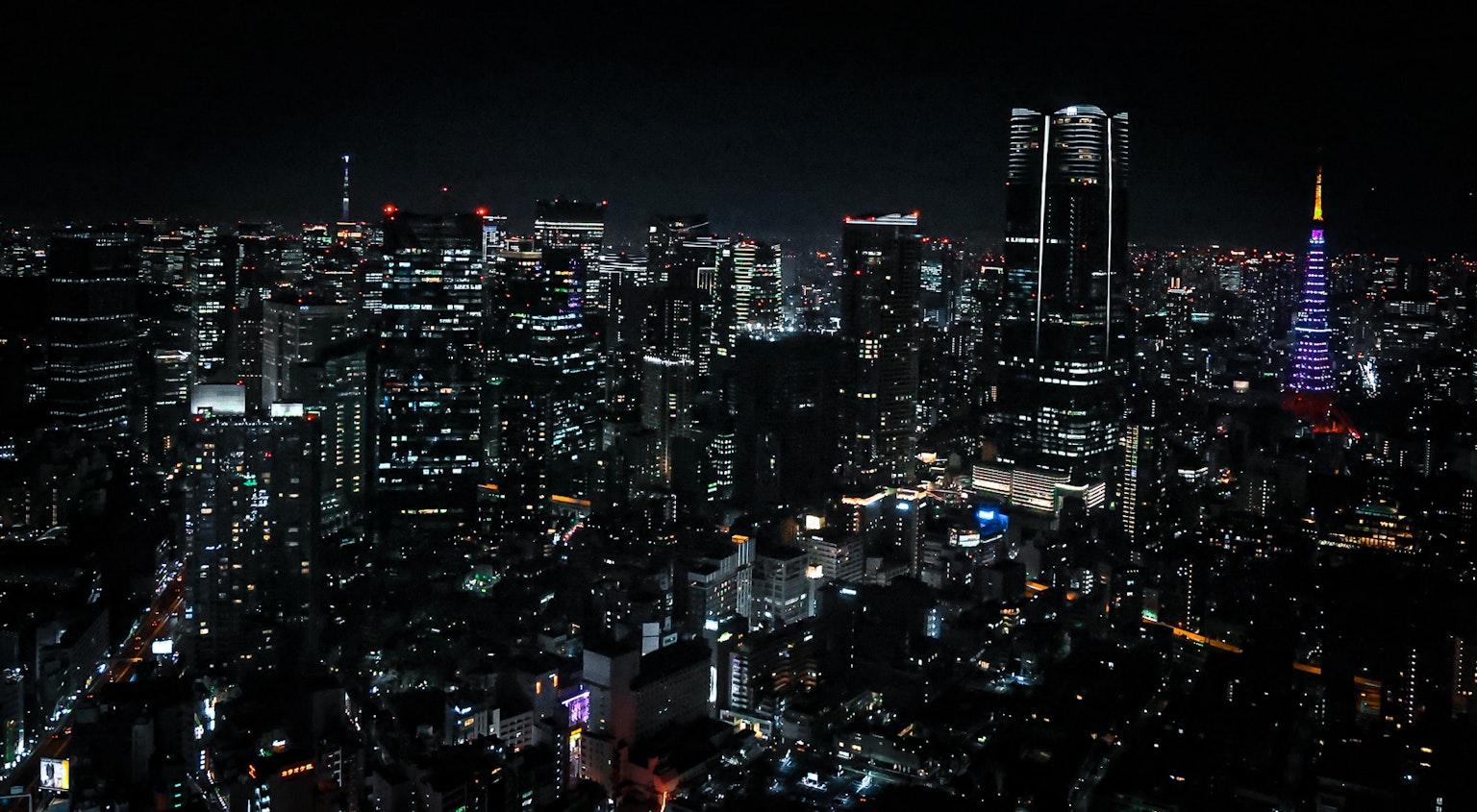 Skyline notturna di Tokyo con grattacieli e un mare di luci con la Torre di Tokyo illuminata