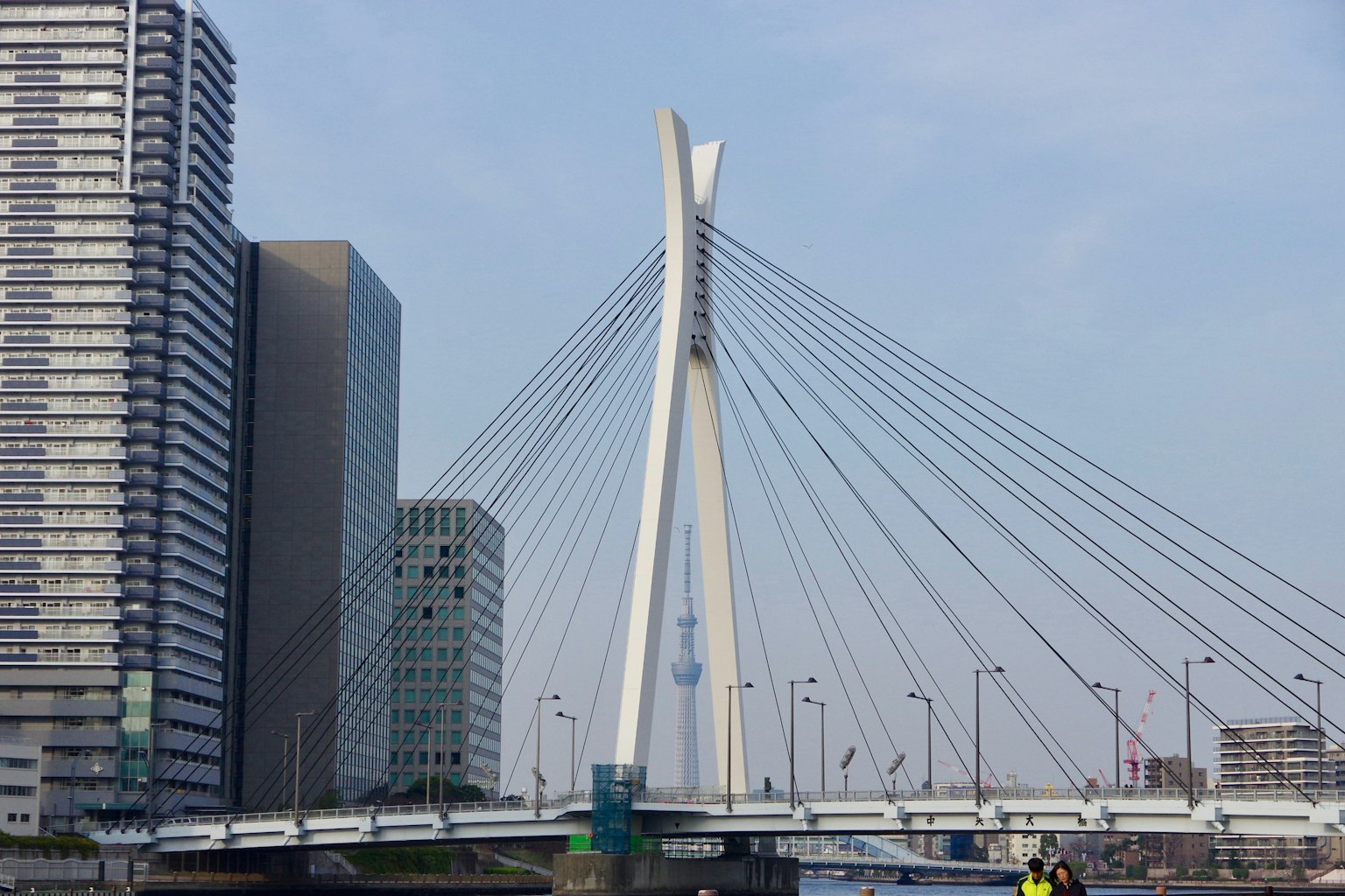Jembatan gantung modern dengan gedung pencakar langit di latar belakang