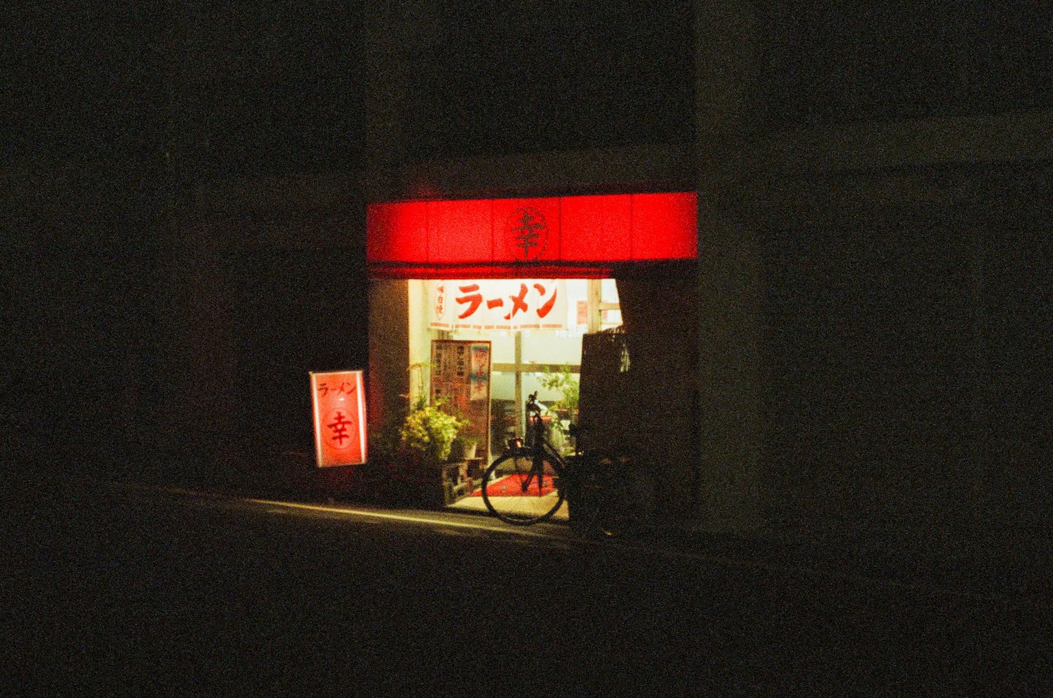 夜间拉面店外观红色招牌和一辆自行车