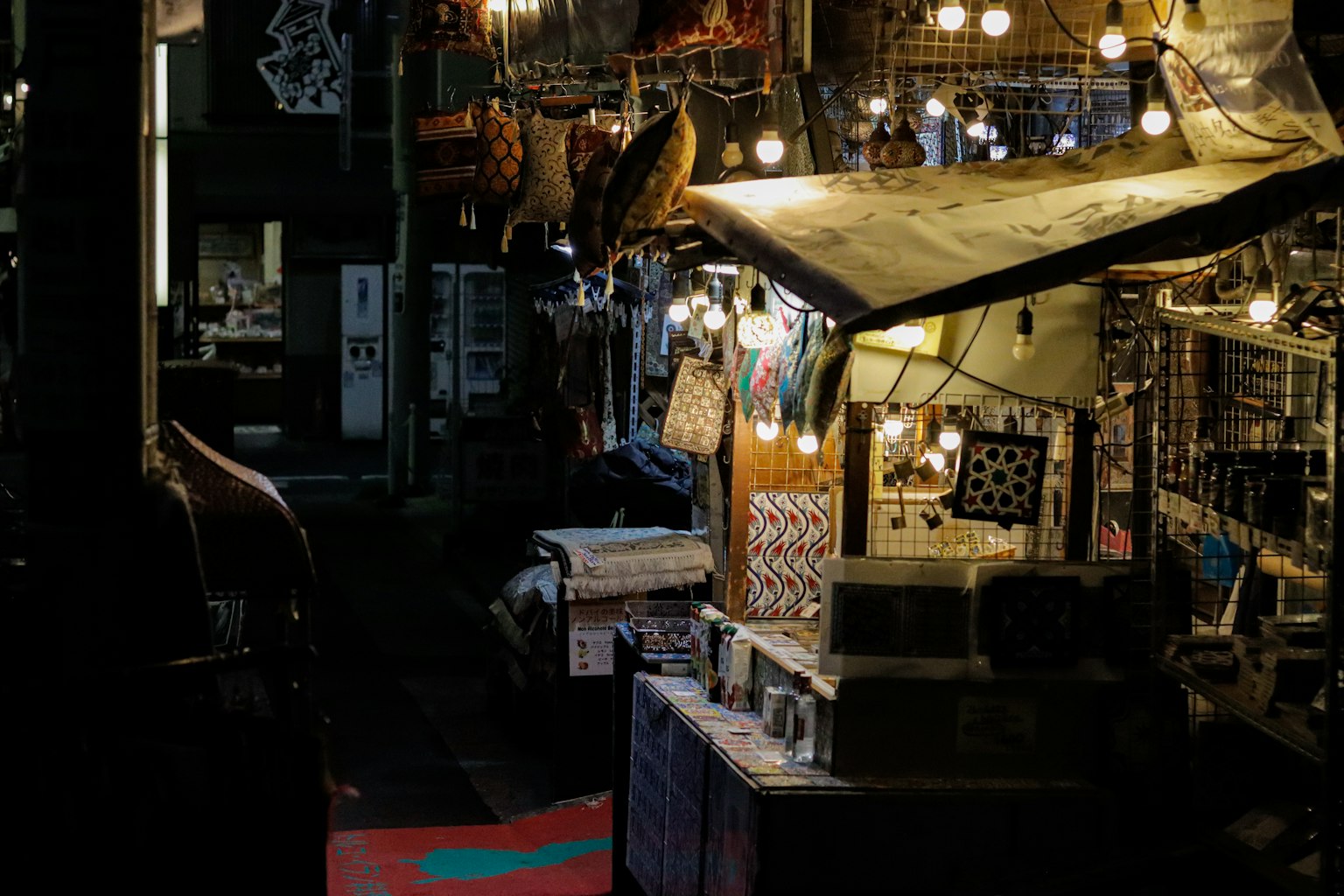 Puesto de mercado débilmente iluminado con lámparas colgantes y varios objetos