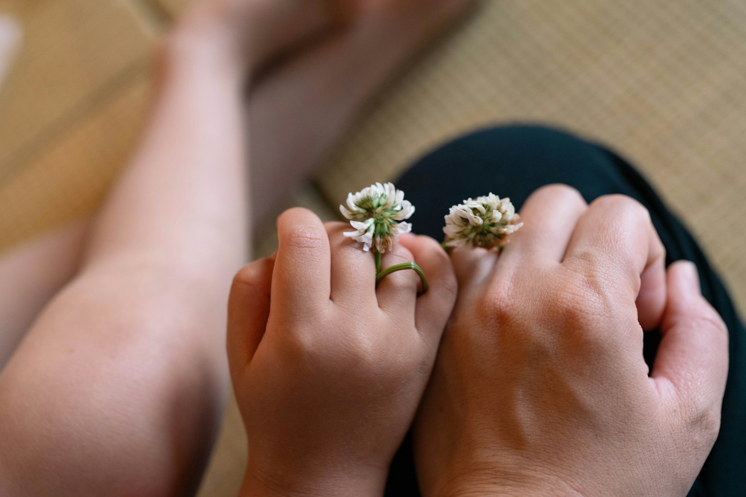 A child's hand and an adult's hand adorned with flower rings
